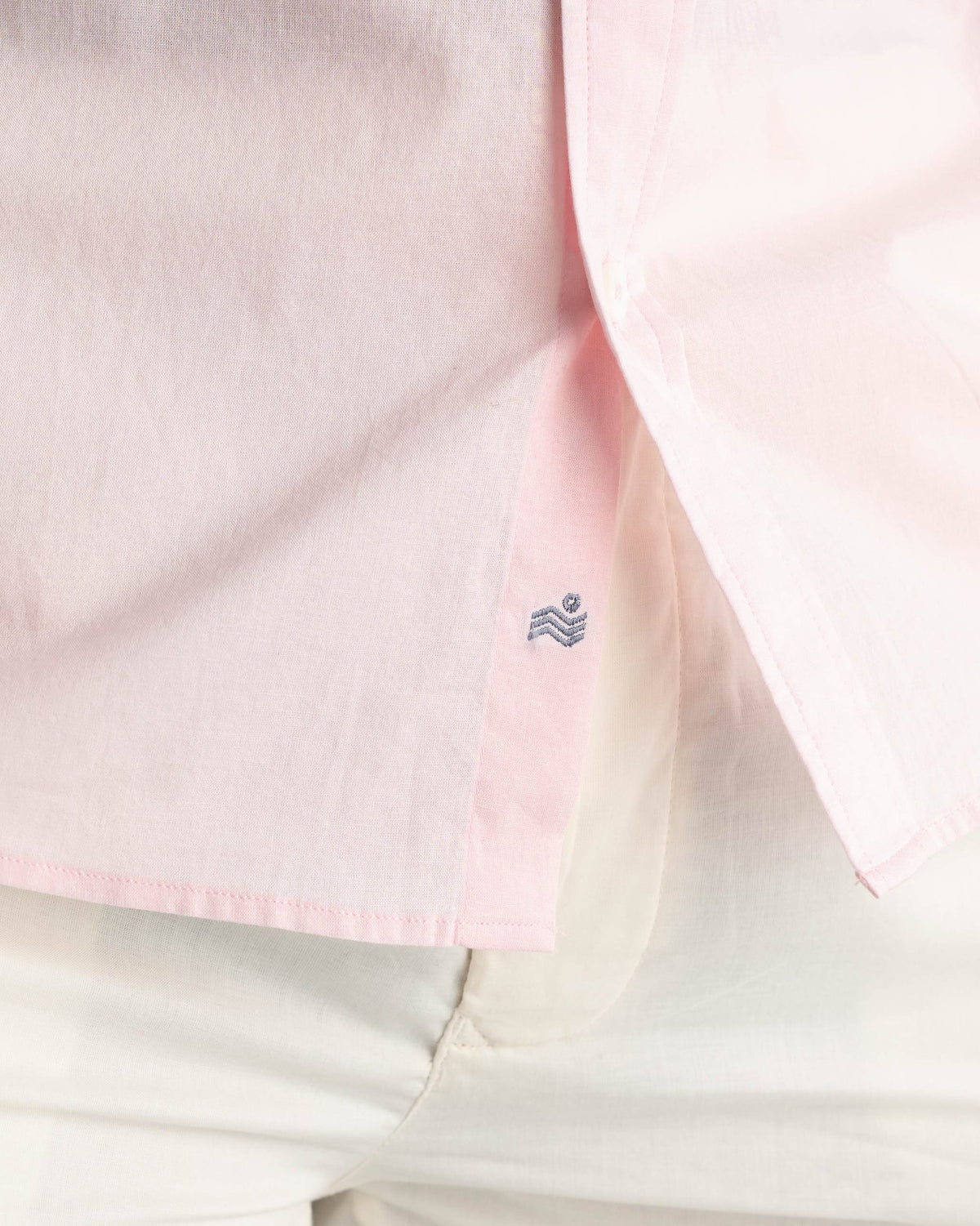 Close-up of a pink Classic Shirt placket with a small blue embroidered logo near the hem.