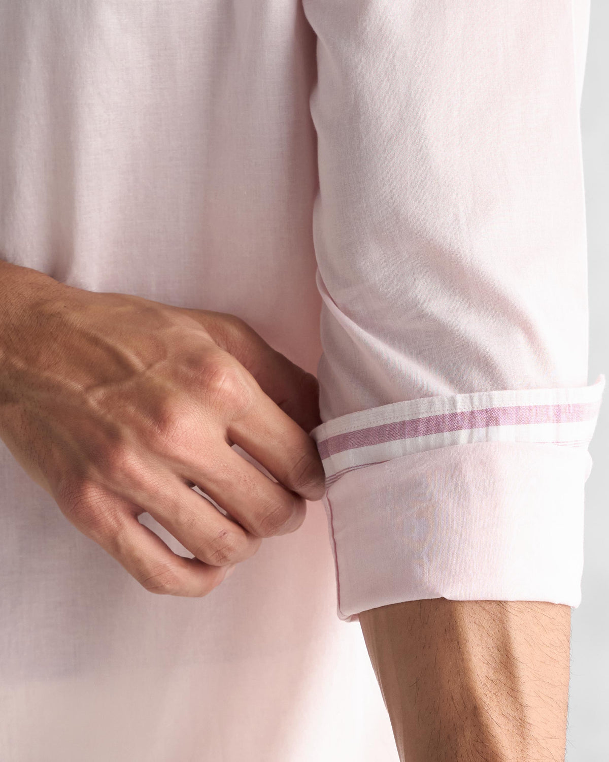 Close-up of a pink Classic Shirt sleeve rolled to show dark pink and white striped lining.