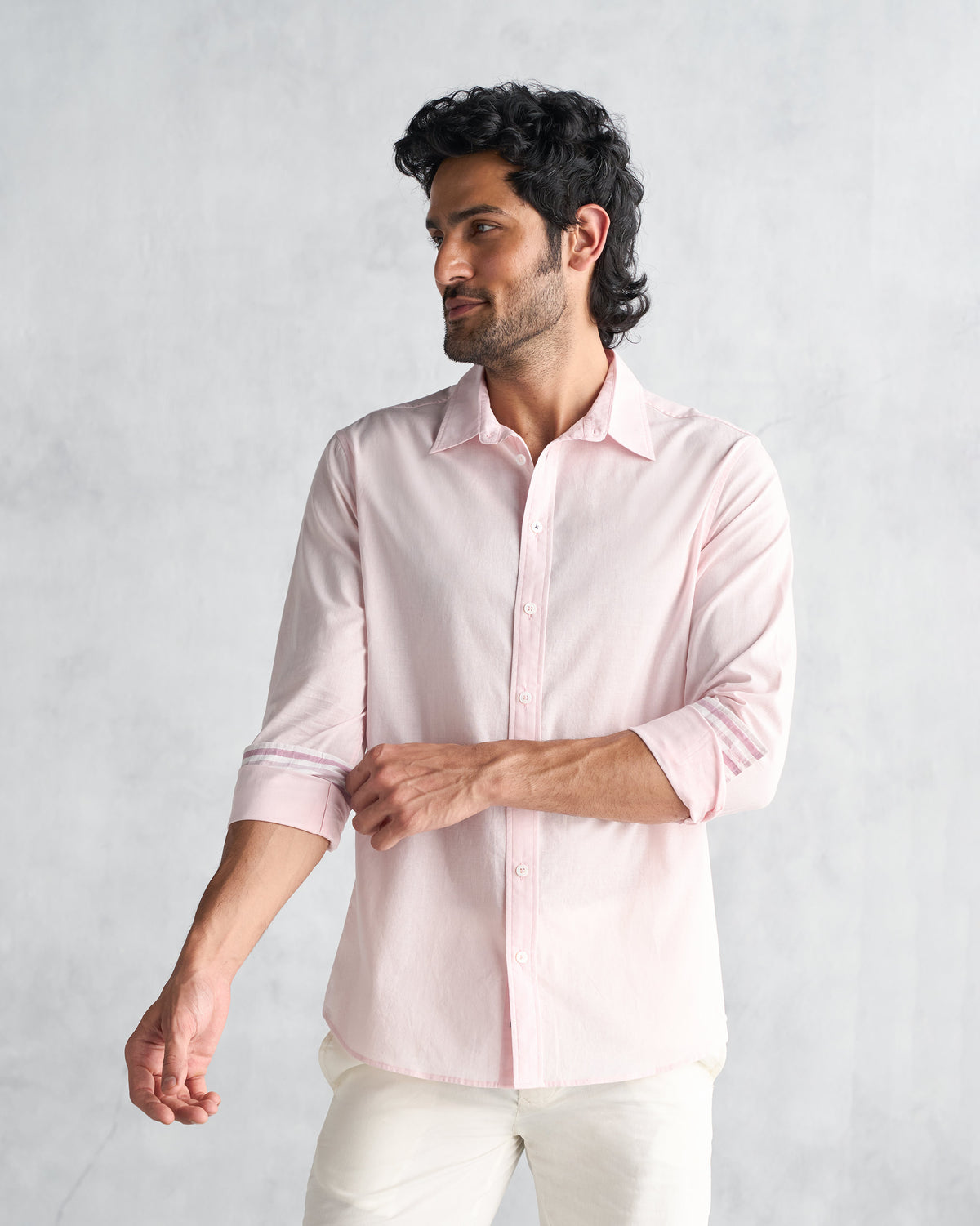 Three-quarter view of a pink Classic Shirt with rolled sleeves and a pointed collar.