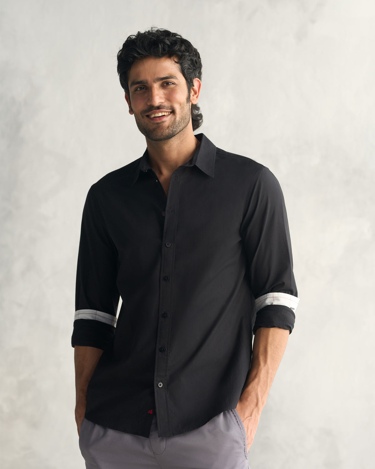 Person wearing a black classic shirt with sleeves rolled to the elbow.