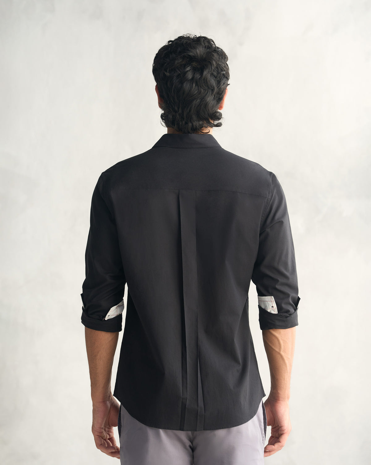 Back of a black classic shirt with a center box pleat.