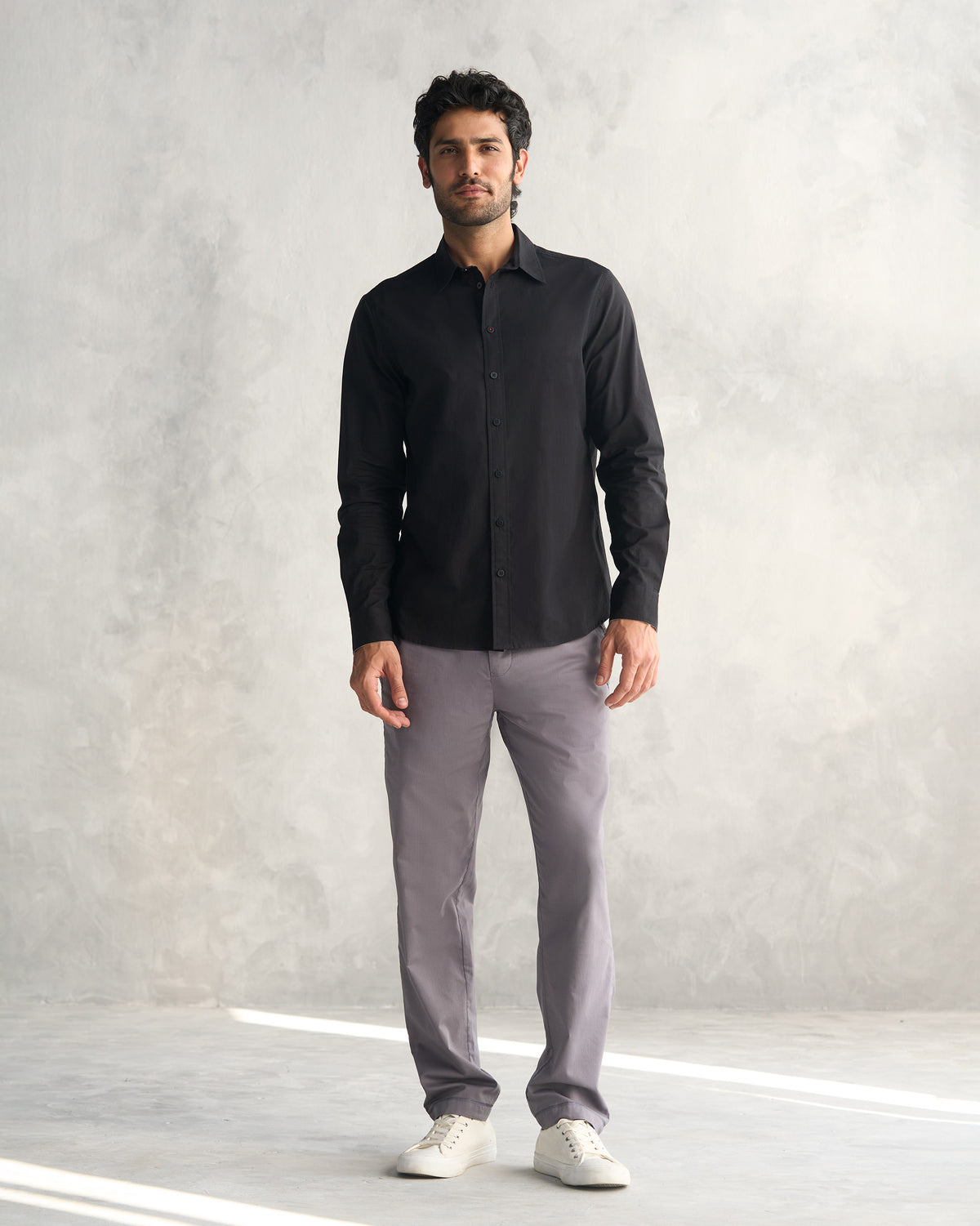 Black classic shirt worn untucked with grey trousers.
