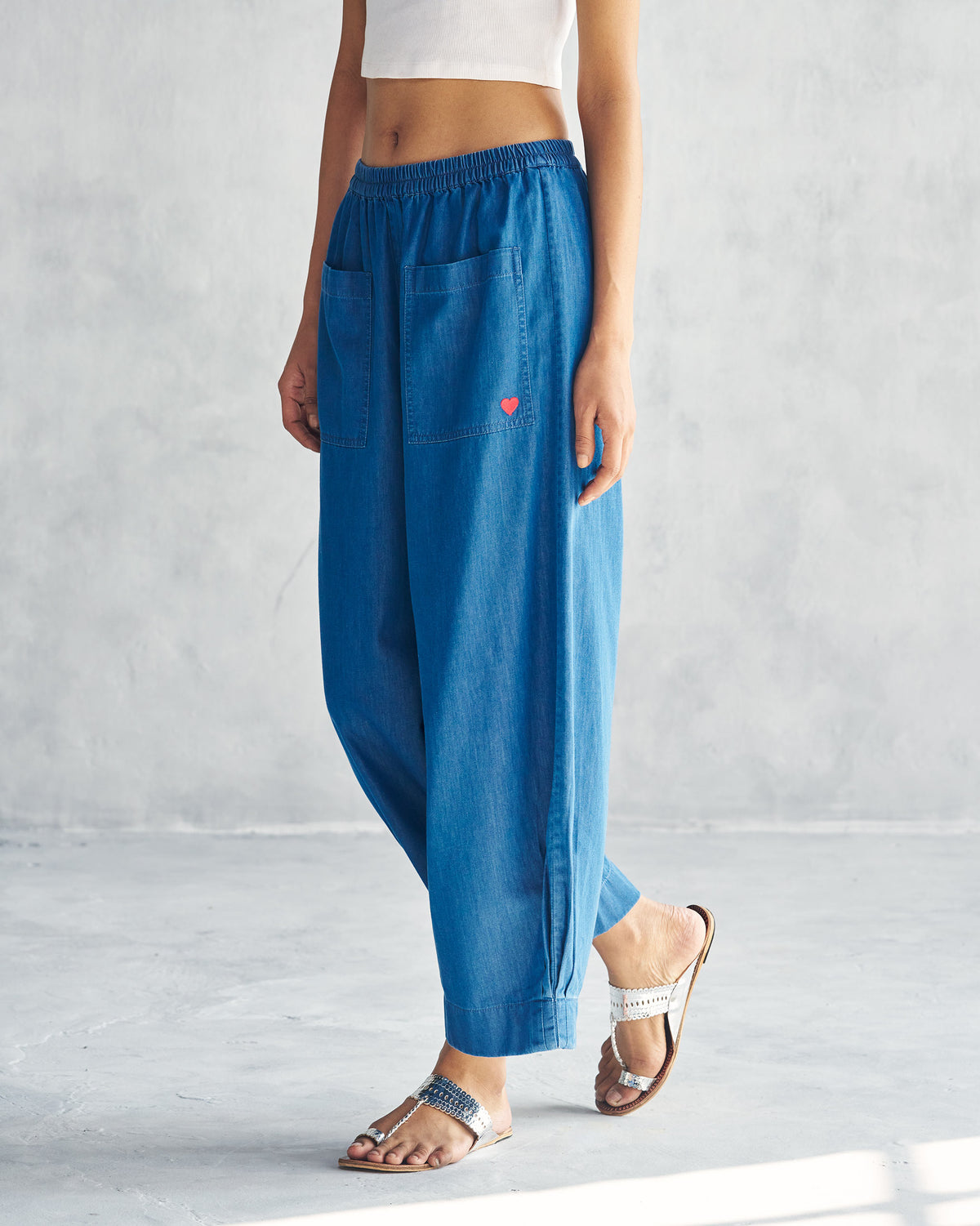 Side view of blue Serene pants showing wide legs and a buttoned ankle slit.