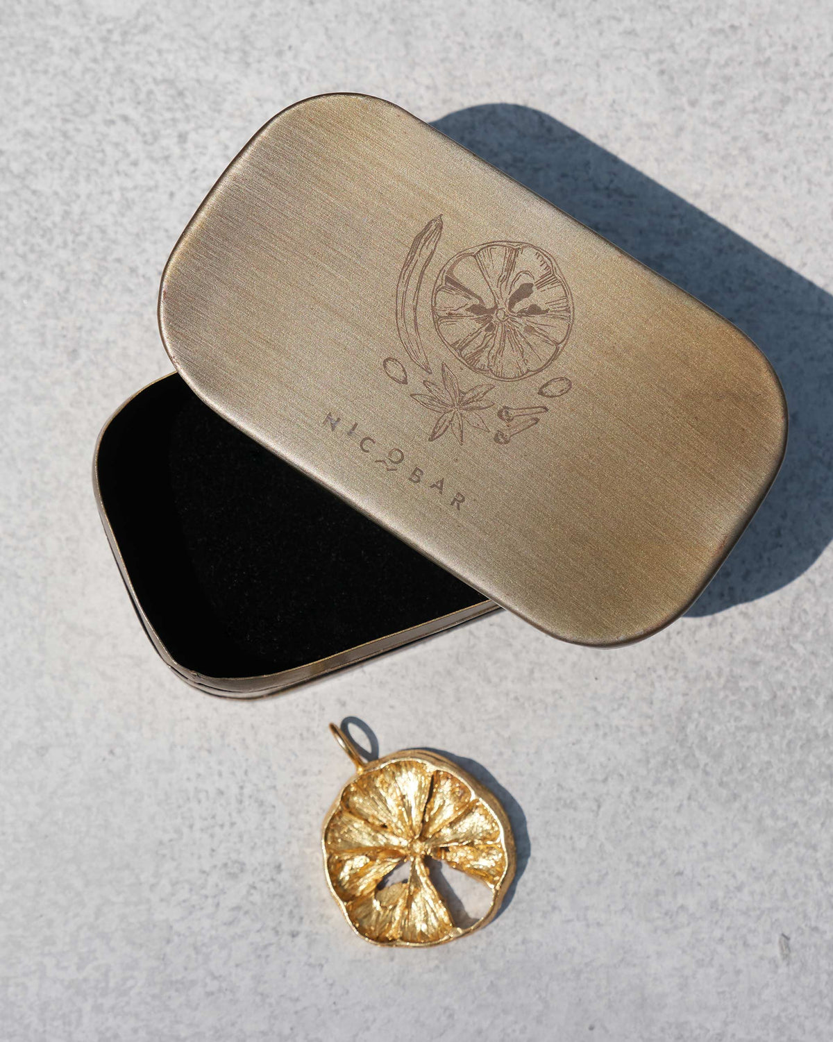 Gold lemon slice charm with its Nicobar spice gift tin.