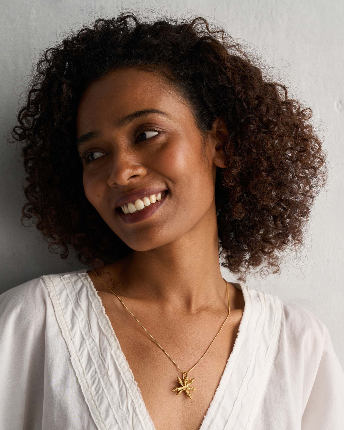 Person wearing a gold Star Anise charm on a fine chain.