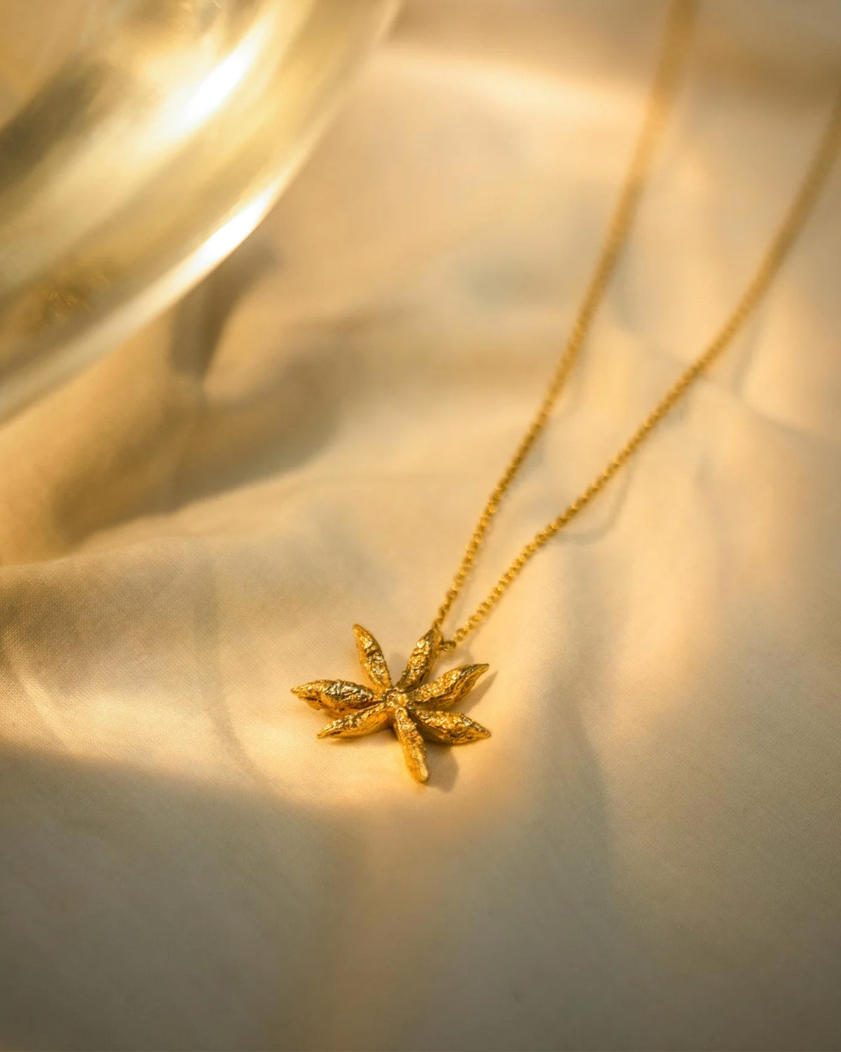 Large gold Star Anise charm pendant on fabric.