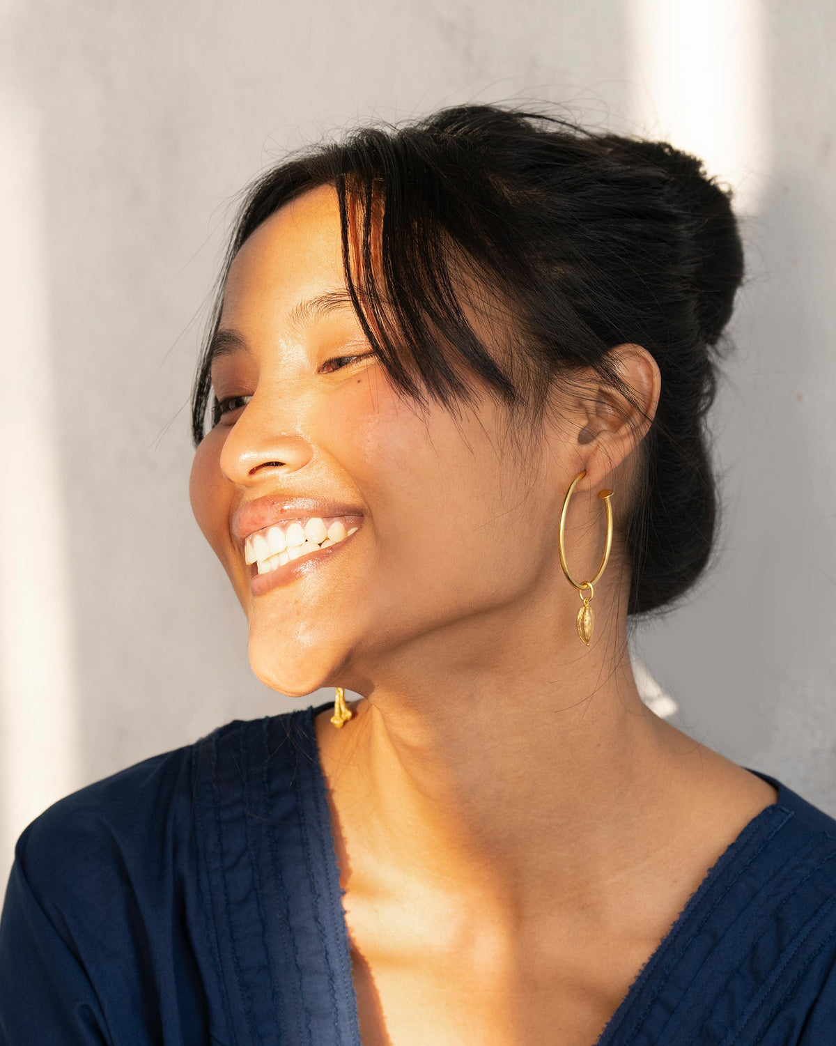 Gold Cardamom charms dangling from thin gold hoop earrings.