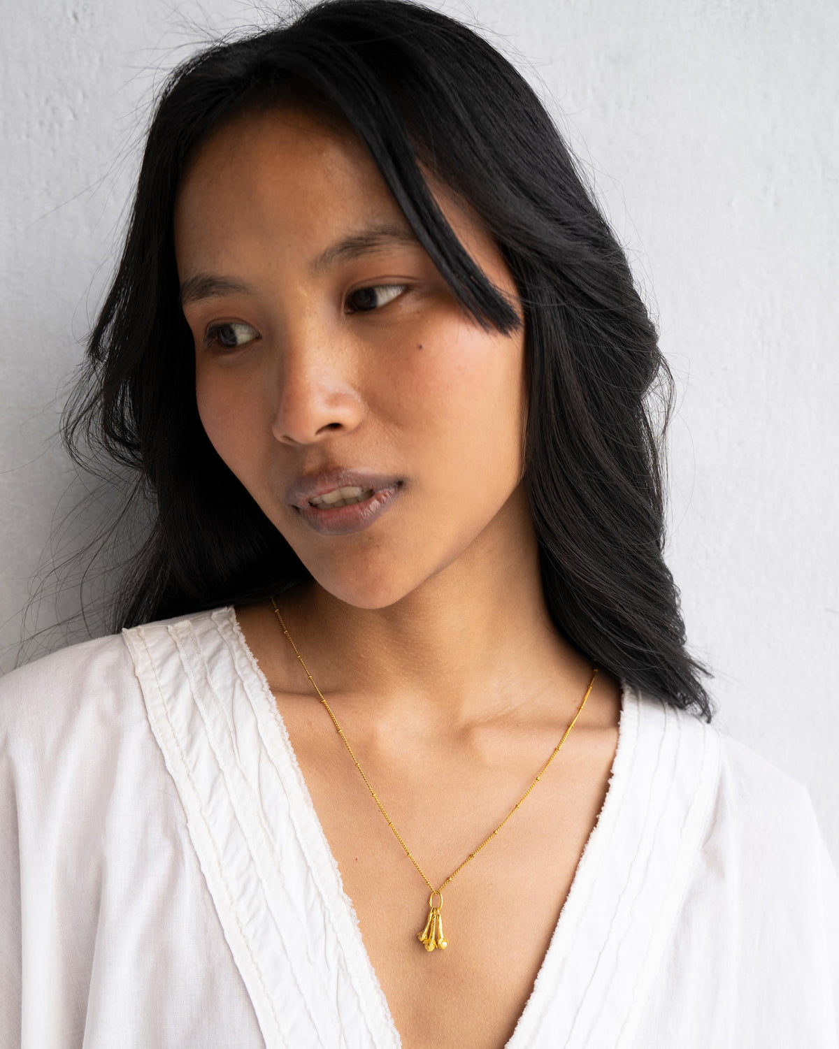 Person wearing a cluster of three gold clove charms.