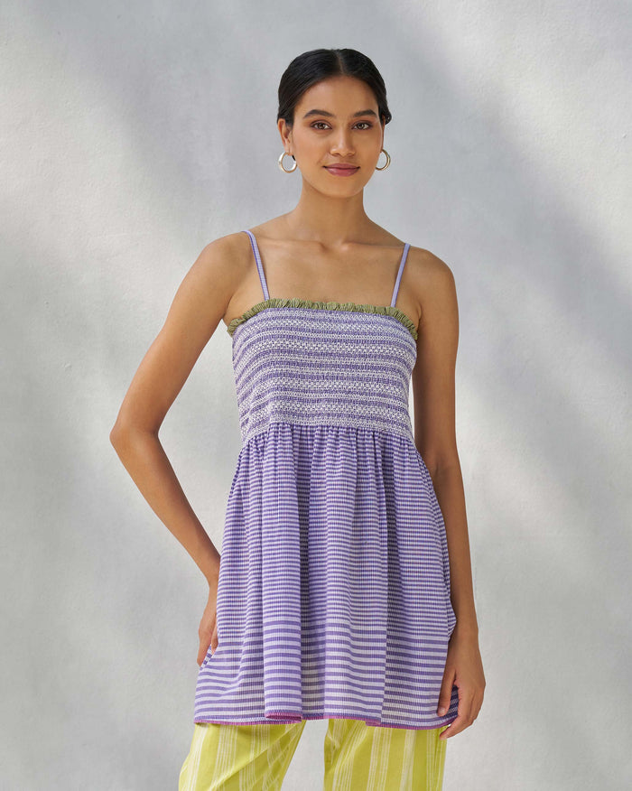 Person wearing a purple and white Paradise top with a smocked bodice and thin straps.