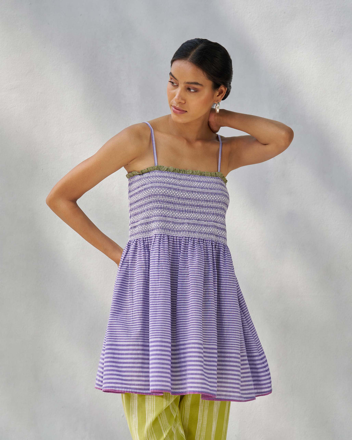 Person wearing a purple and white Paradise top with horizontal stripes and a smocked bodice.
