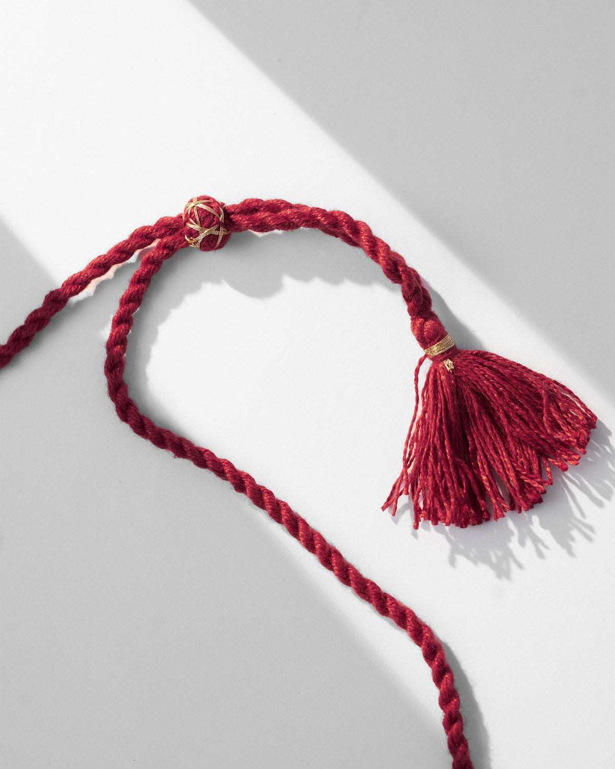 Close-up of the maroon cord and gold-wrapped tassel on a coco palm necklace.