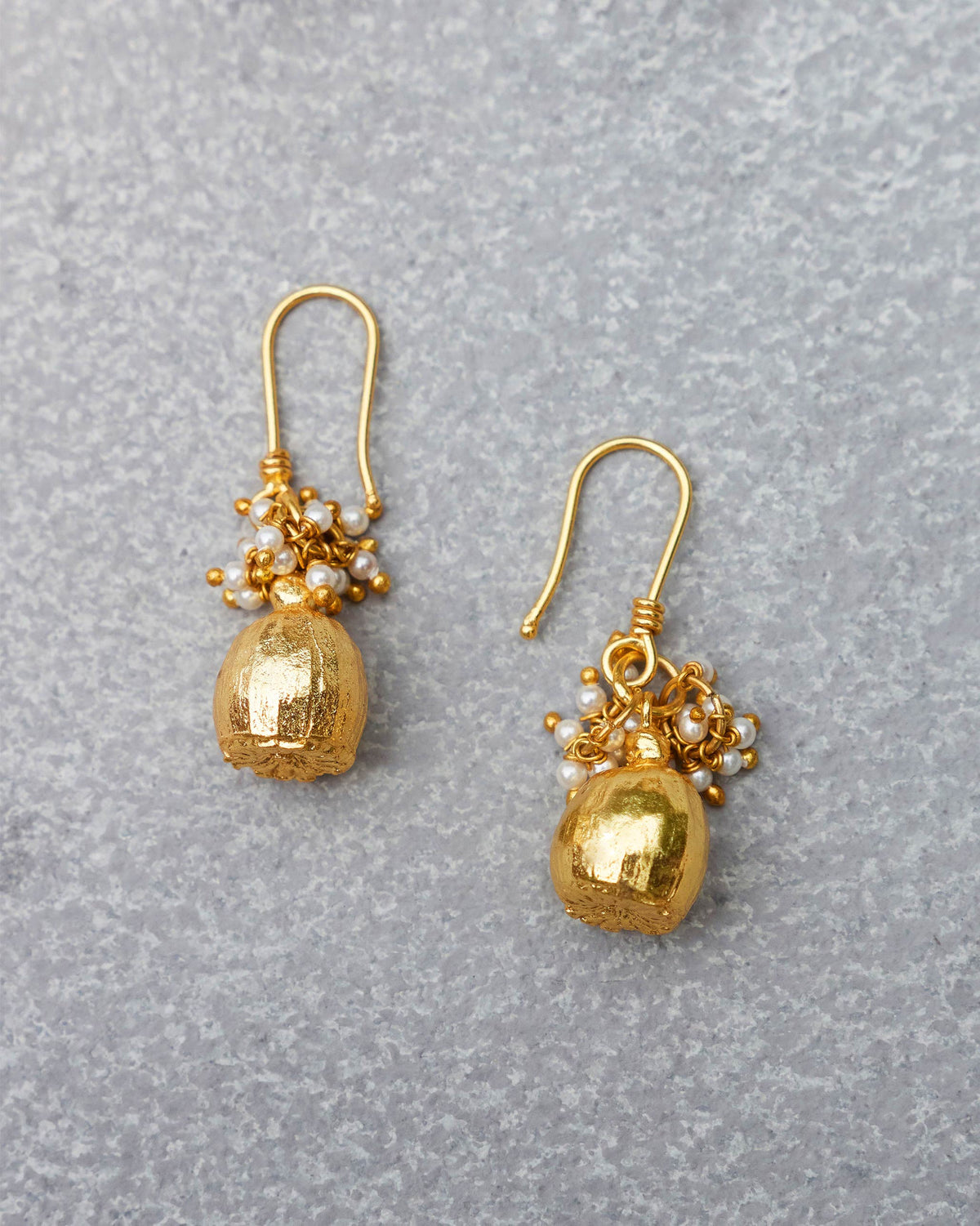 Pair of gold Pearl Poppy Drop Earrings with pearl clusters laid flat.