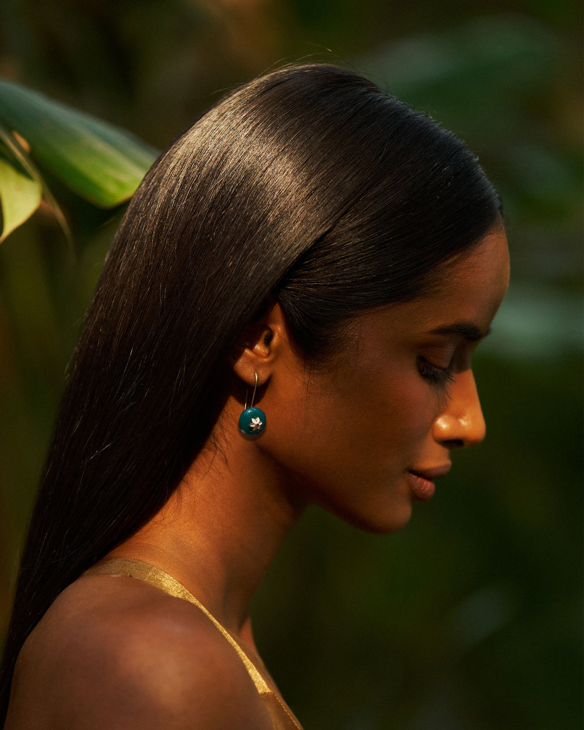 Side profile of a green onyx Aurora earring with a small flower motif.