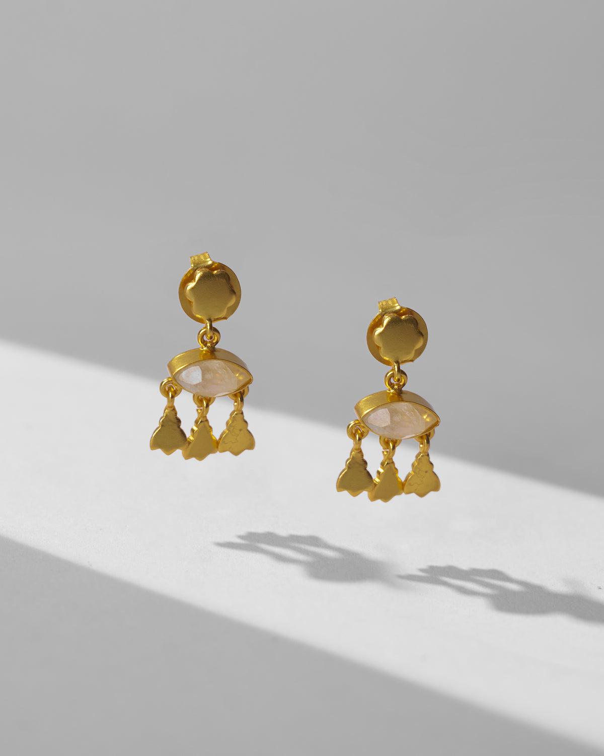 Pair of gold Jhalak earrings with moonstone and leaf charms.