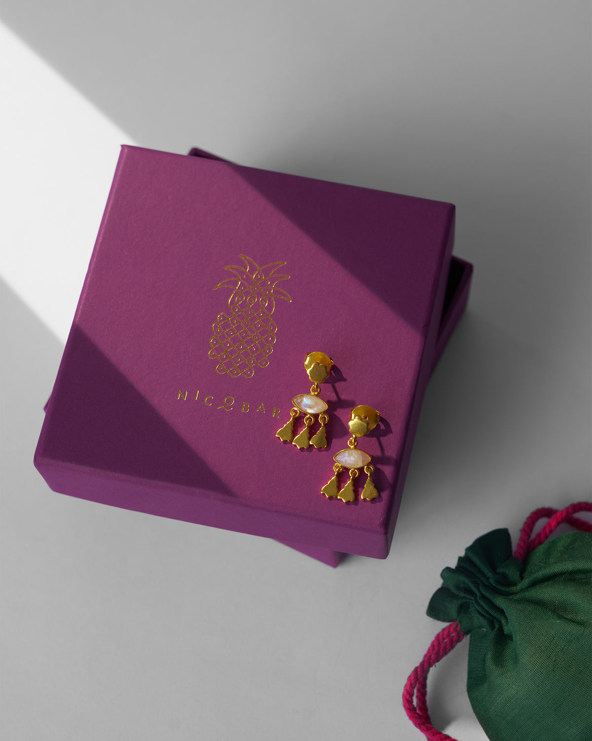 Gold Jhalak earrings on a purple Nicobar gift box.