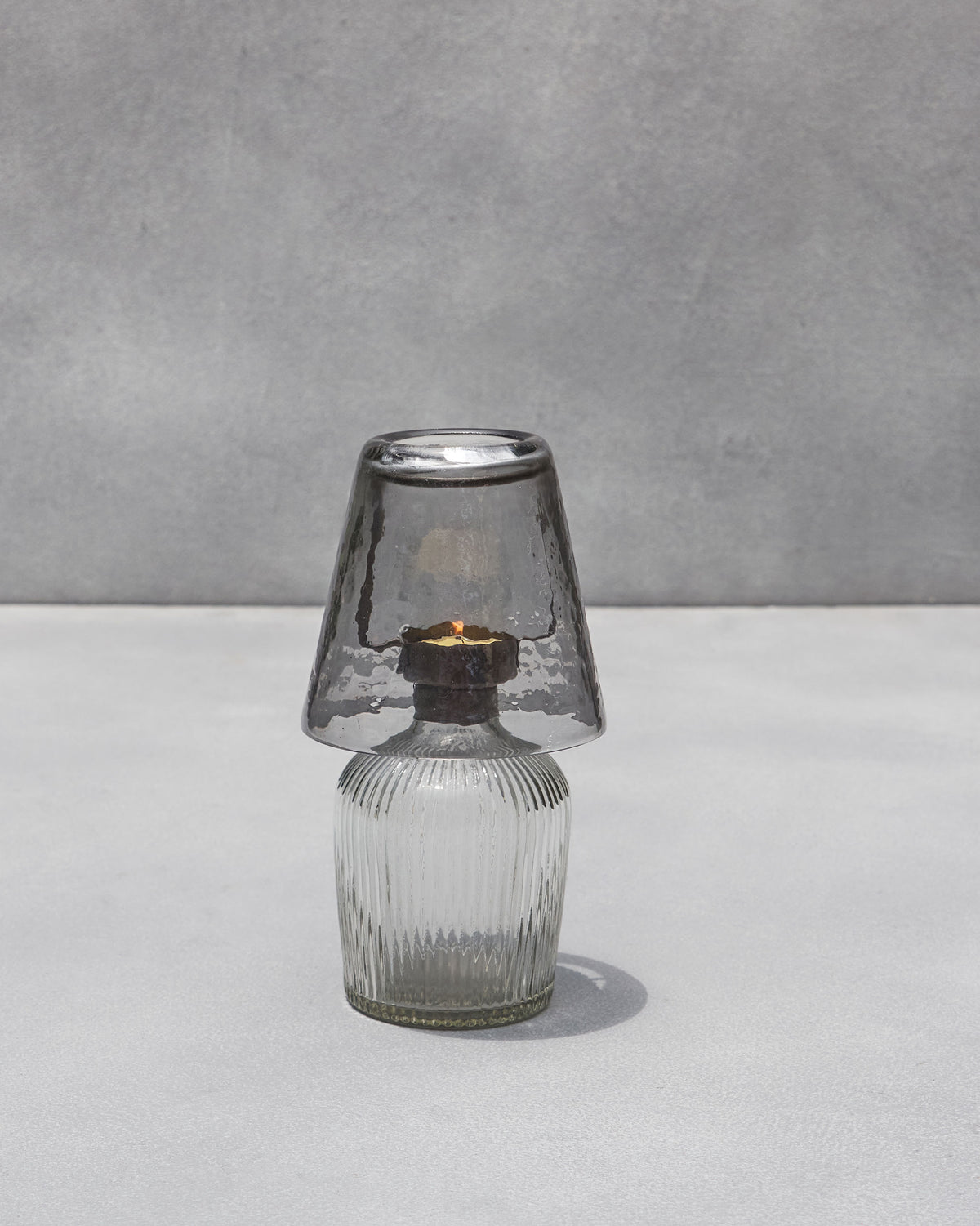 Asfar glass votive with clear ribbed base and smoky shade, candle lit.
