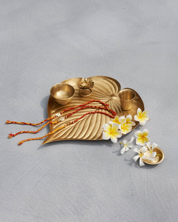 The leaf tray with the marigold incense holder, bowls, thread and frangipani