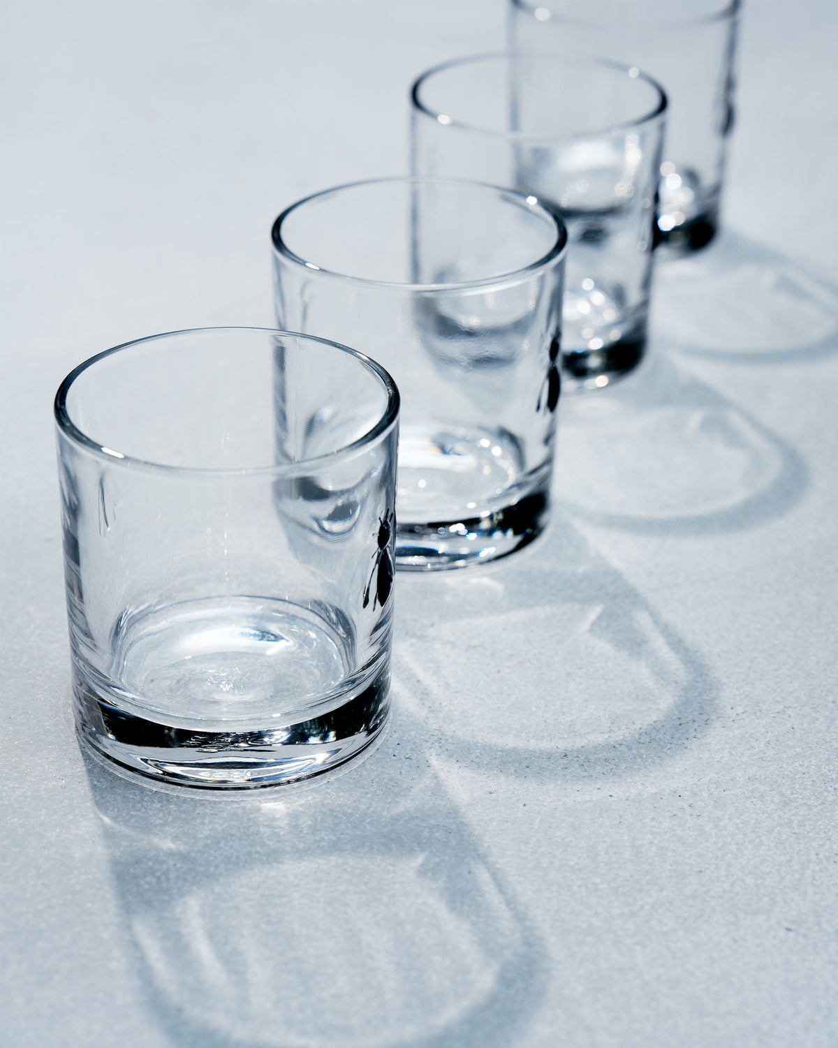 Four Bumble Bee whiskey glasses lined up with a small bee motif.