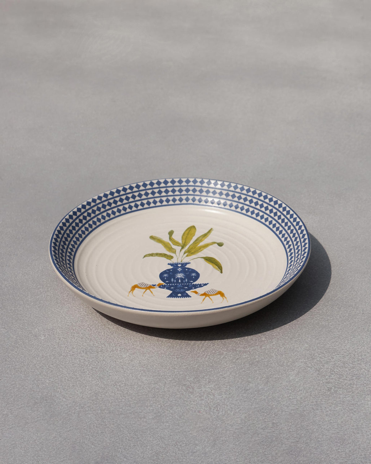 Side view of the Sahara pasta plate with a blue vase.