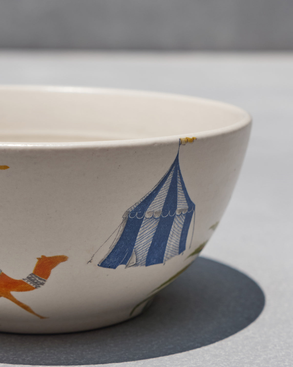 Side view of Asfar Cereal Bowl showing a blue striped tent and an orange animal.