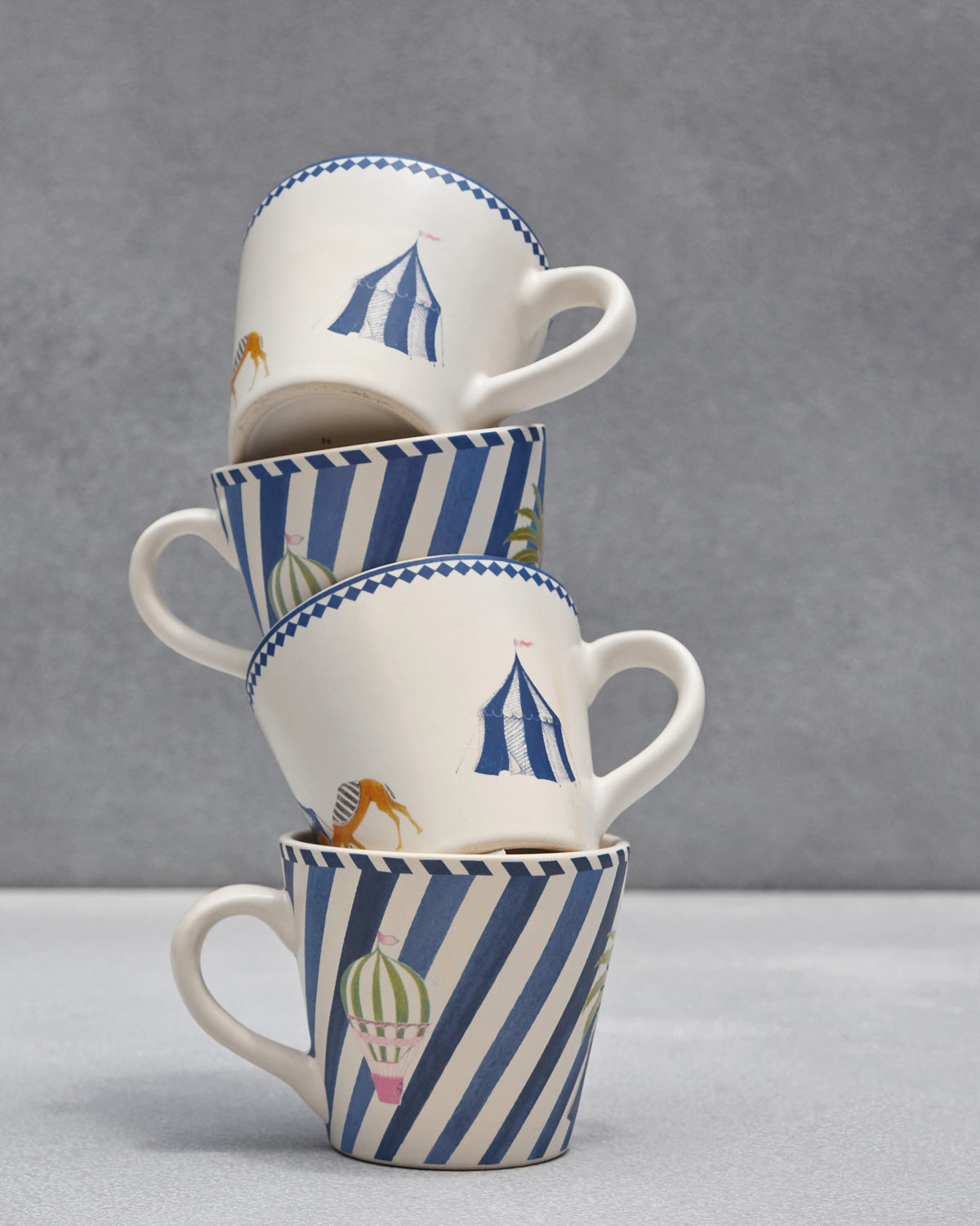 Stack of four Sahara espresso mugs with circus and balloon prints.