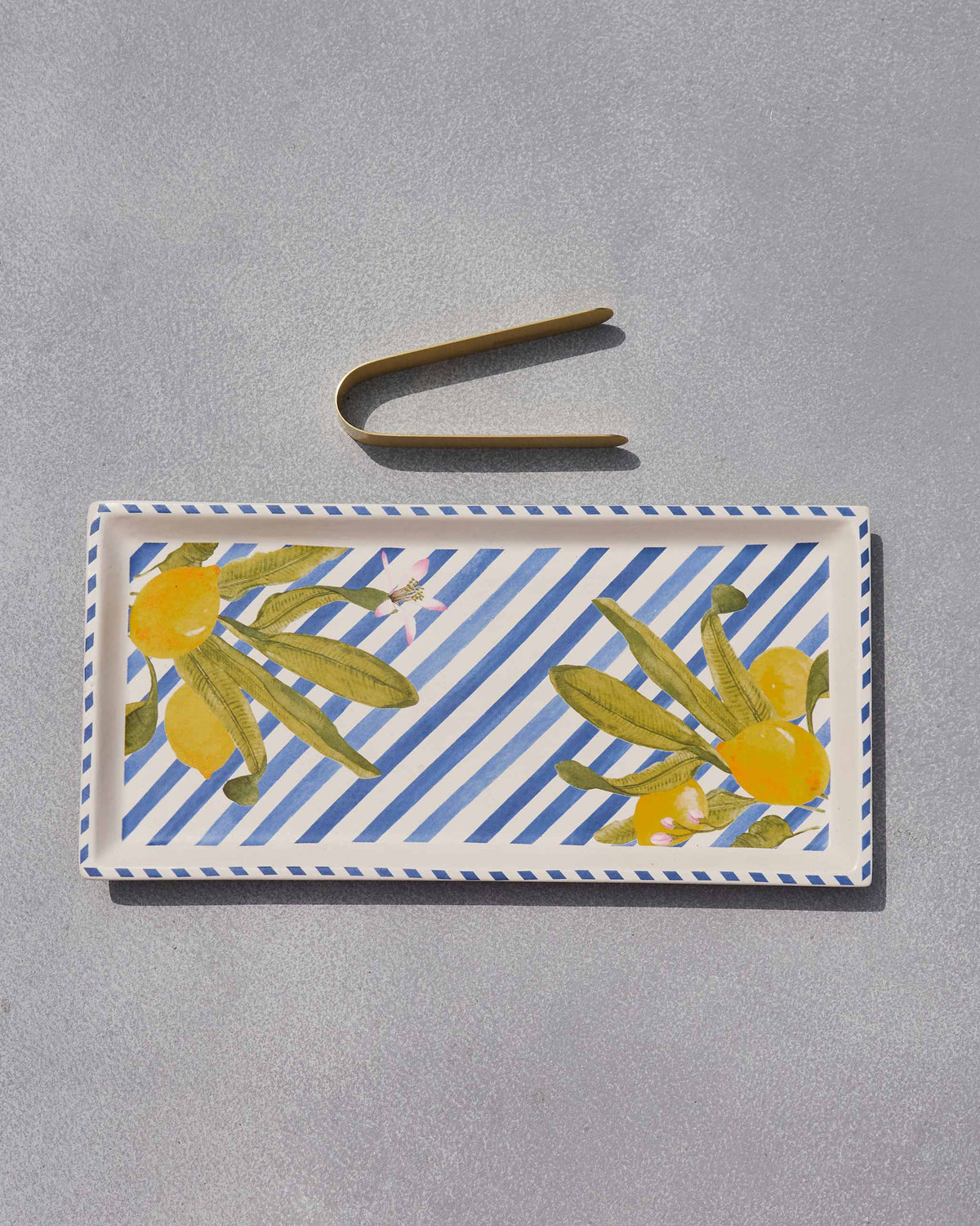 Asfar cookie tray with lemon motifs and gold tongs laid above the rim.