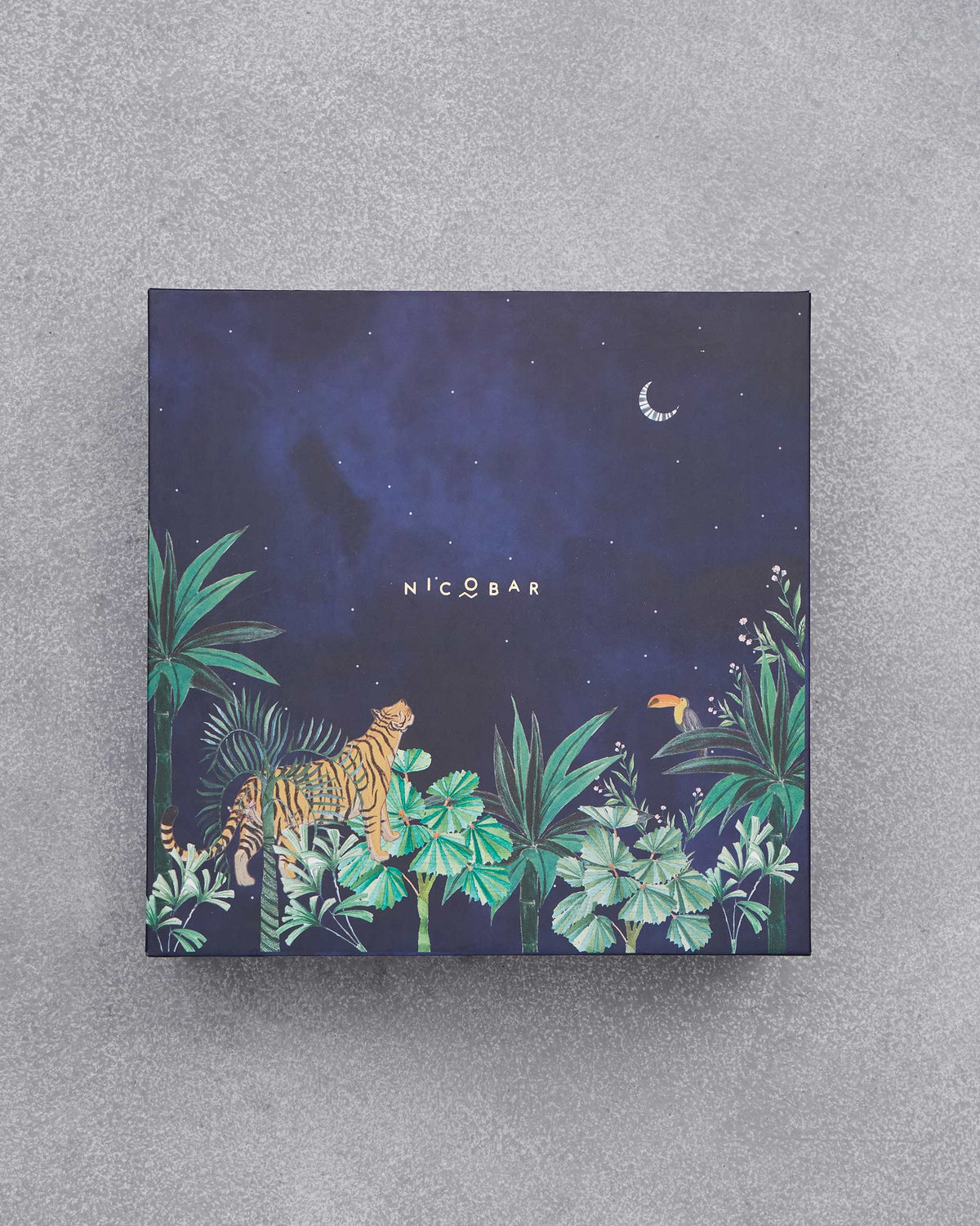 Navy Nicobar gift box with a tiger, toucan, and crescent moon jungle scene.