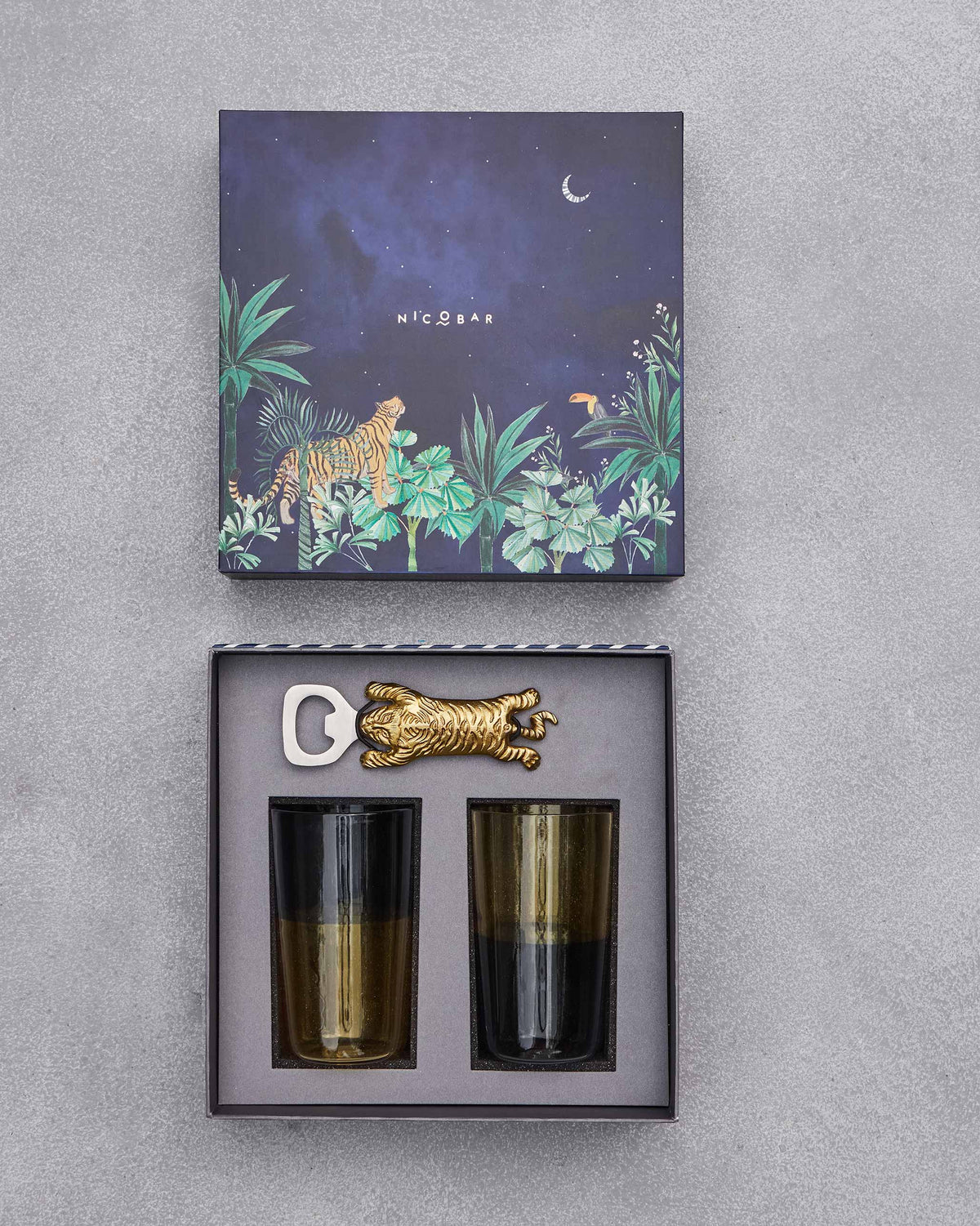 Open Asfar gift box with a tiger bottle opener and two amber-smoke glasses.