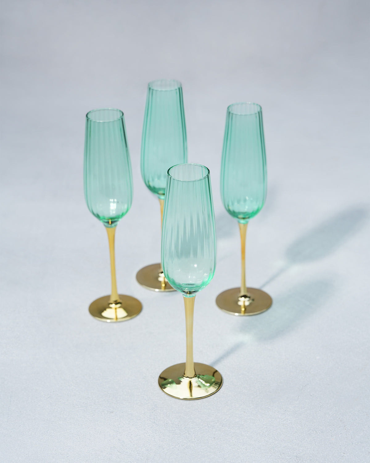 Set of four seafoam green champagne flutes with gold stems.