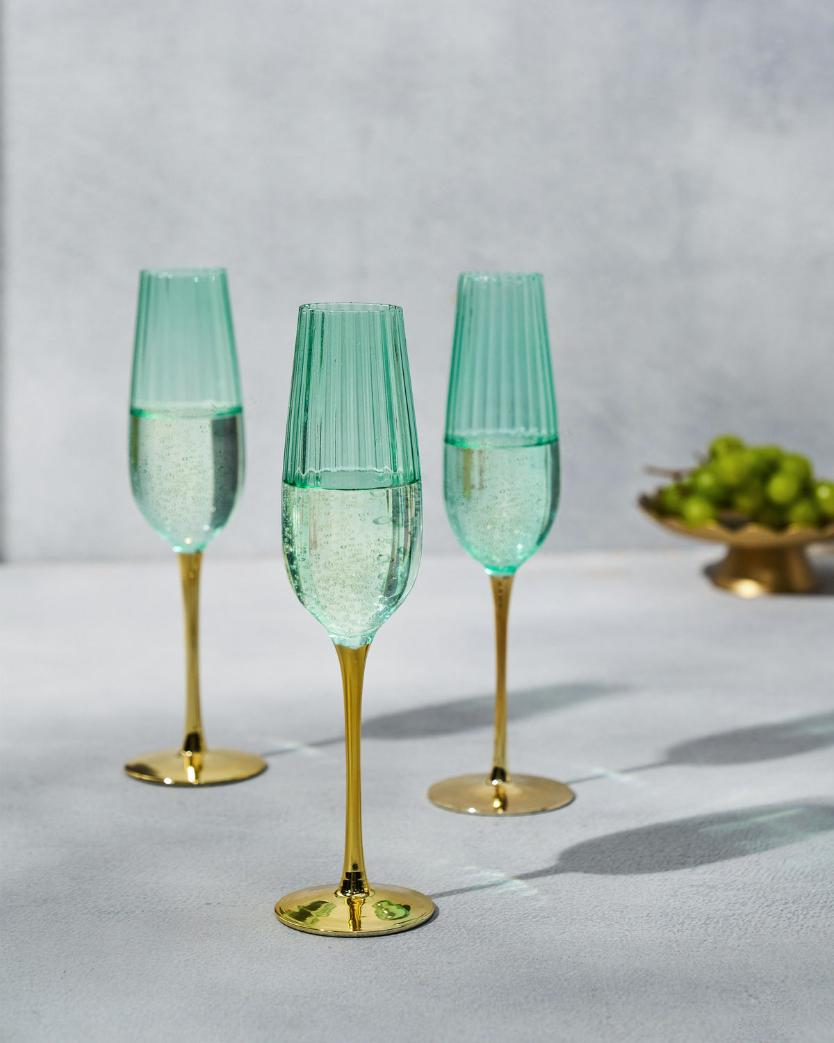 Seafoam green champagne flutes with gold stems.
