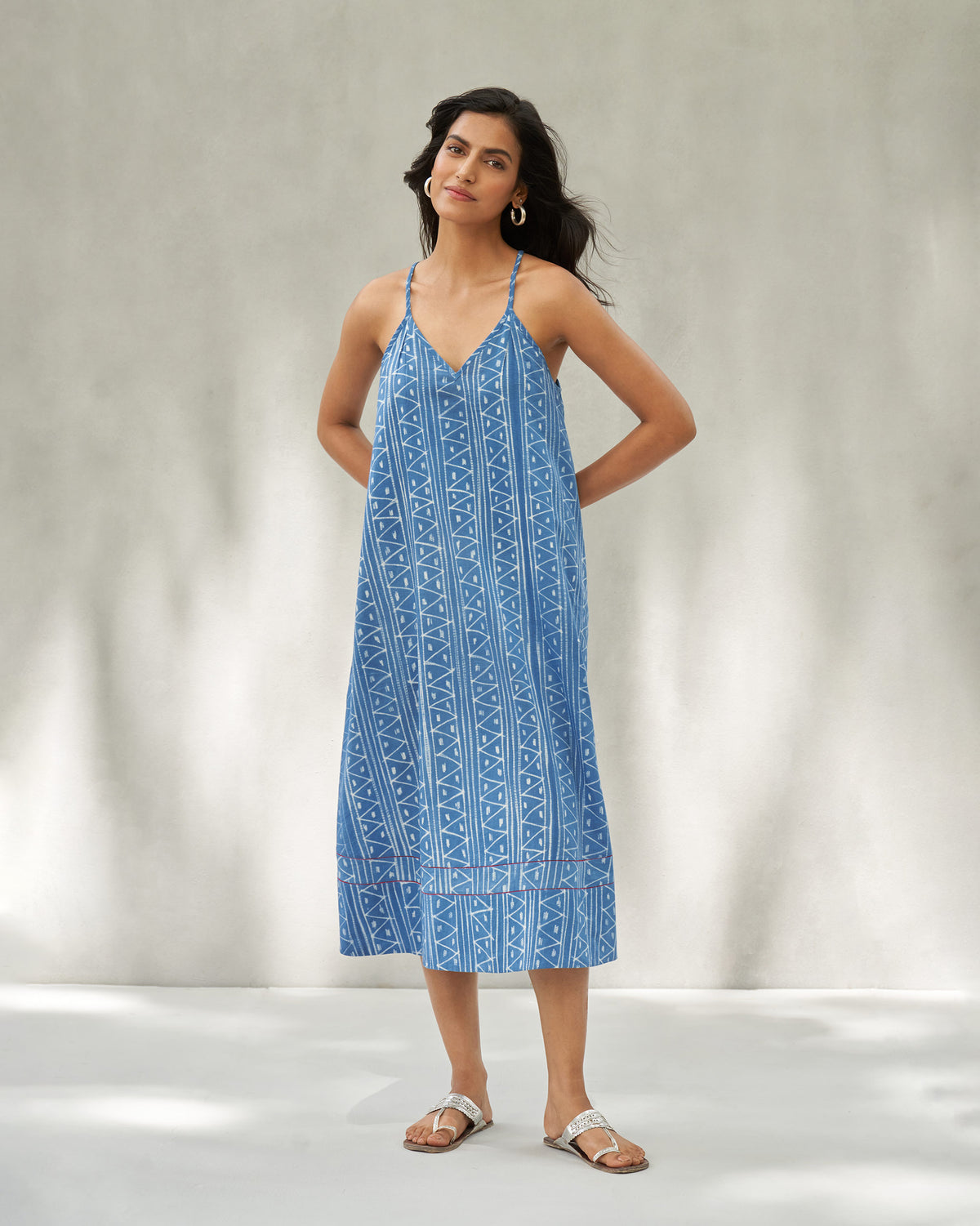 Person wearing a blue strappy midi dress with white tribal geometric print.