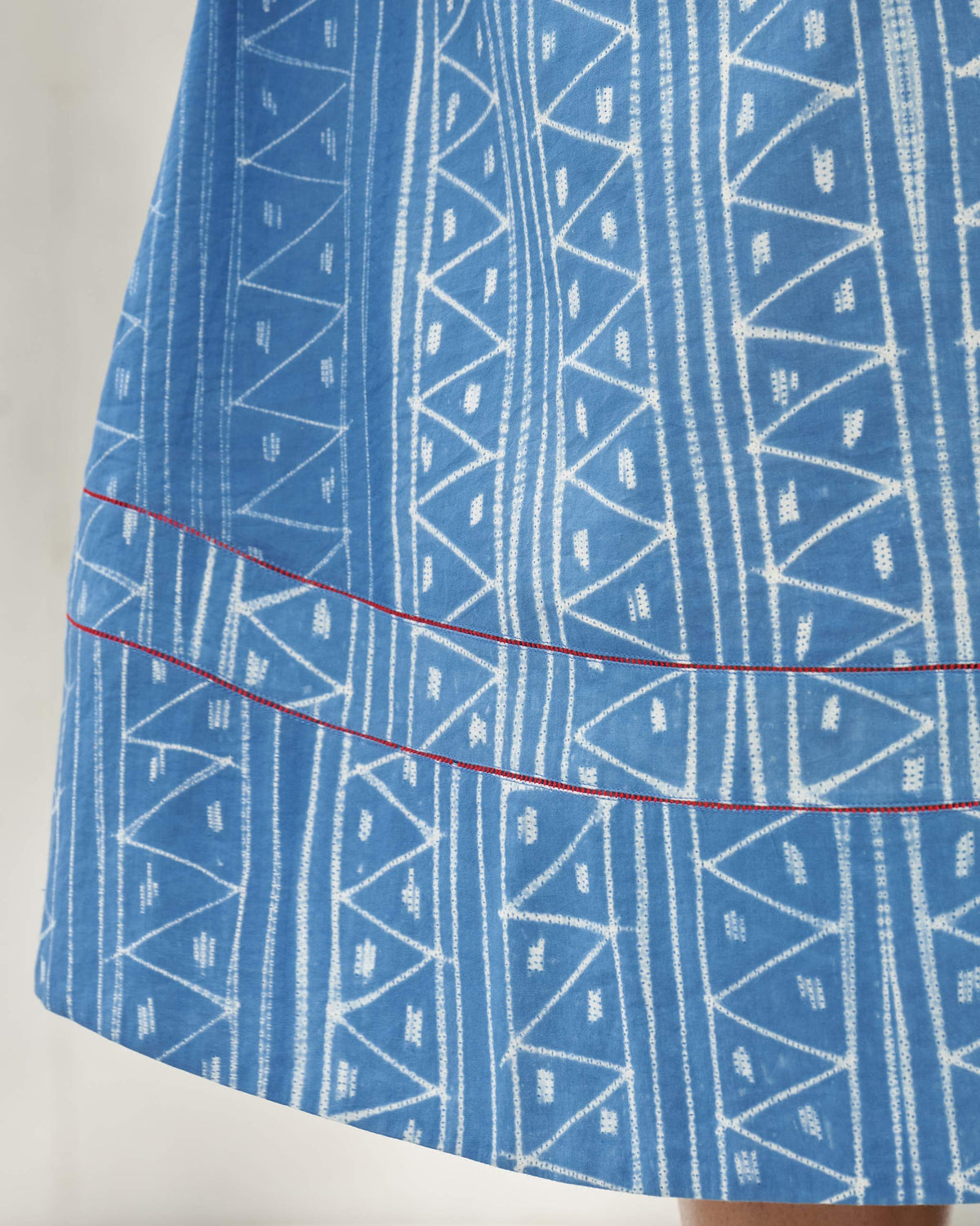 Close-up of blue tribal geometric print and red contrast lines near the dress hem.