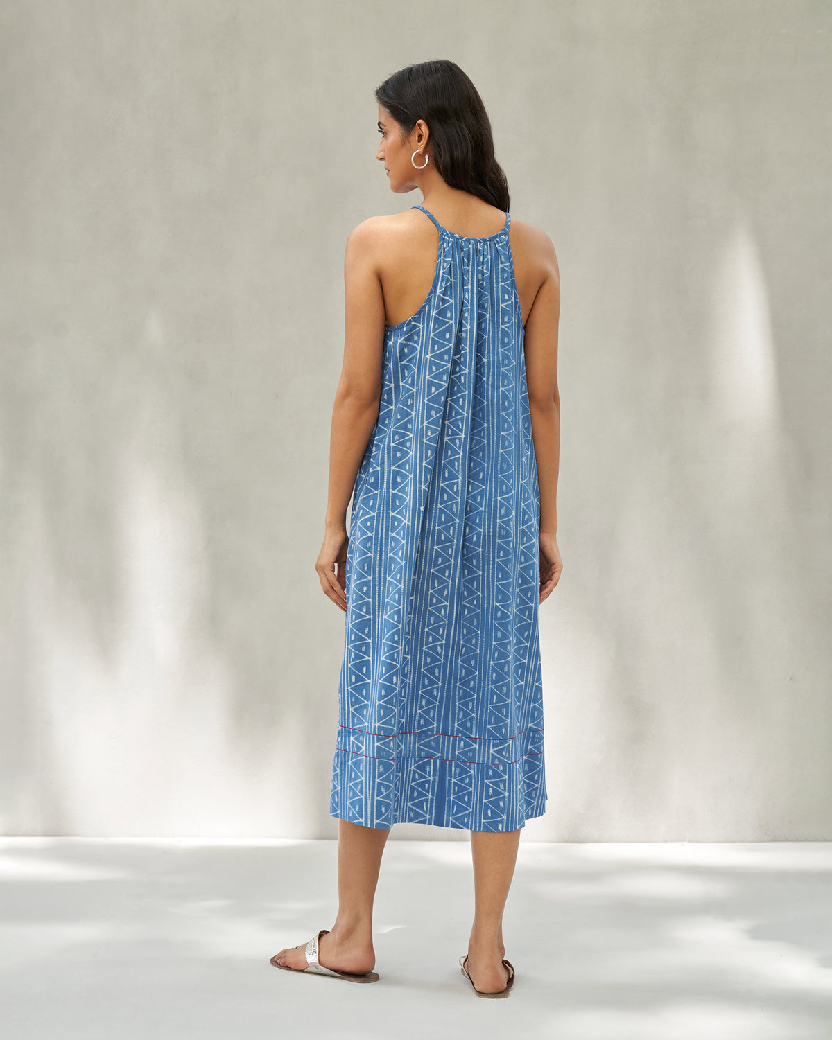 Back of a blue strappy midi dress with an open upper back and geometric print.