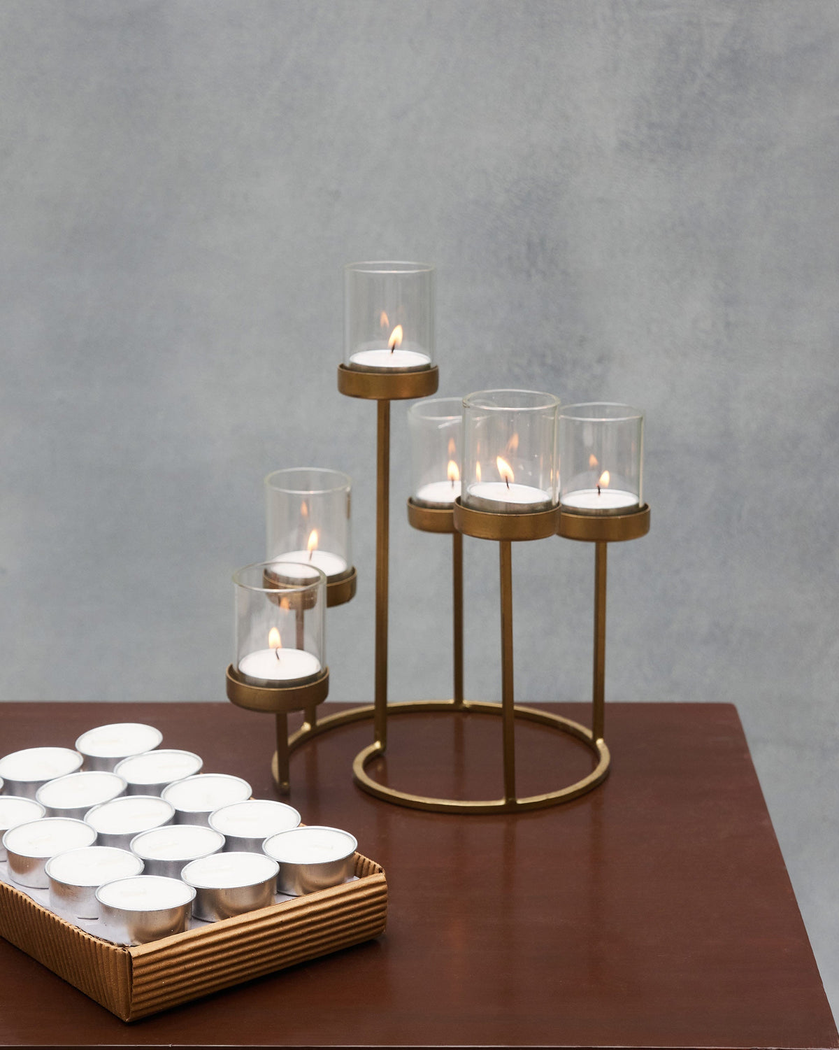 Madurai tealights lit in a brass tiered holder beside the packed set.