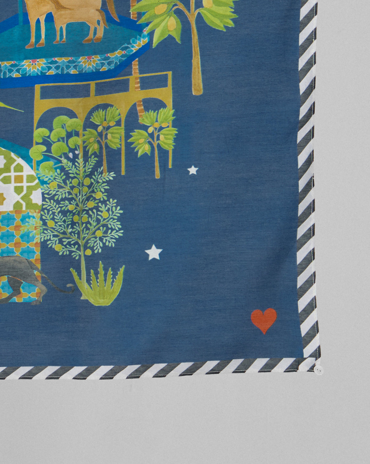 Close-up of a Midnight Carnival scarf corner showing palm trees, a small heart and a striped edge.
