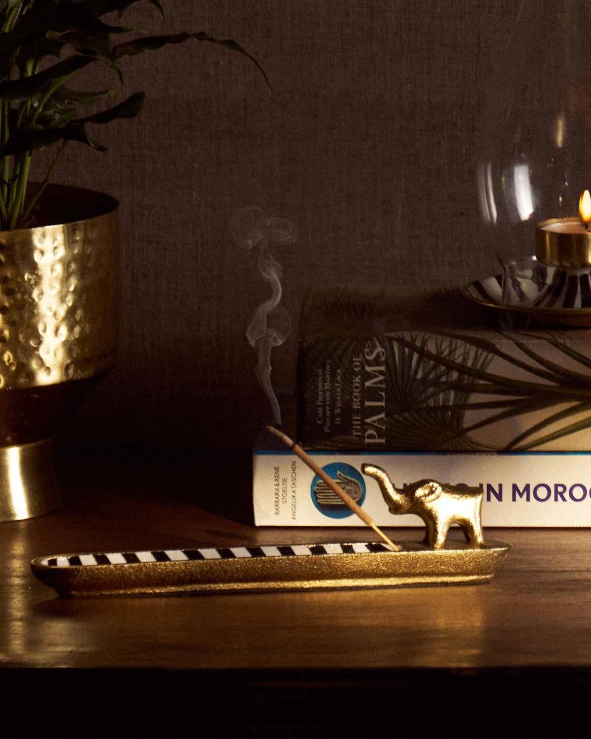 Brass Haathi incense holder with black and white stripes and lit incense.