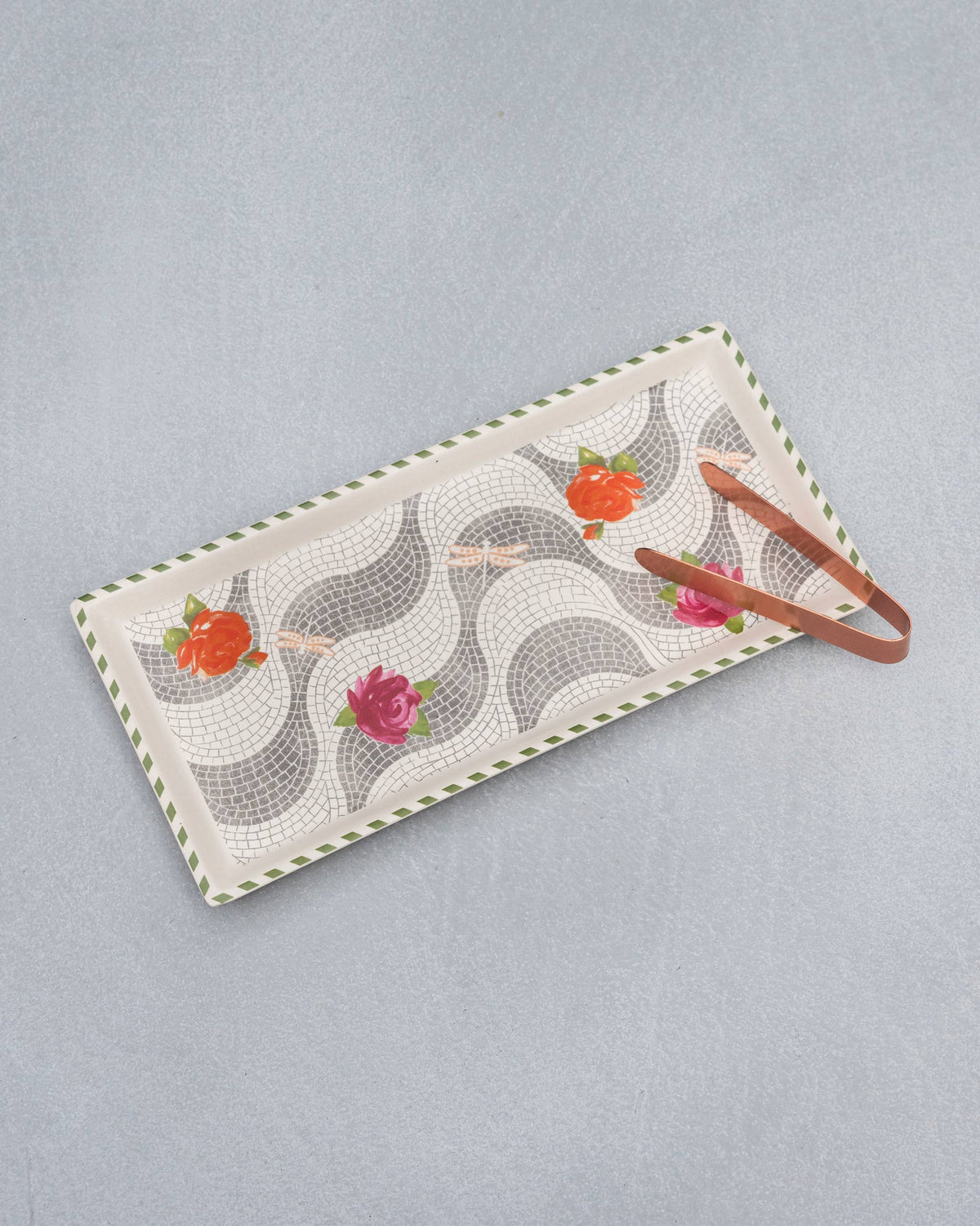Mosaic Bloom cookie tray with copper tongs resting on the floral mosaic surface.