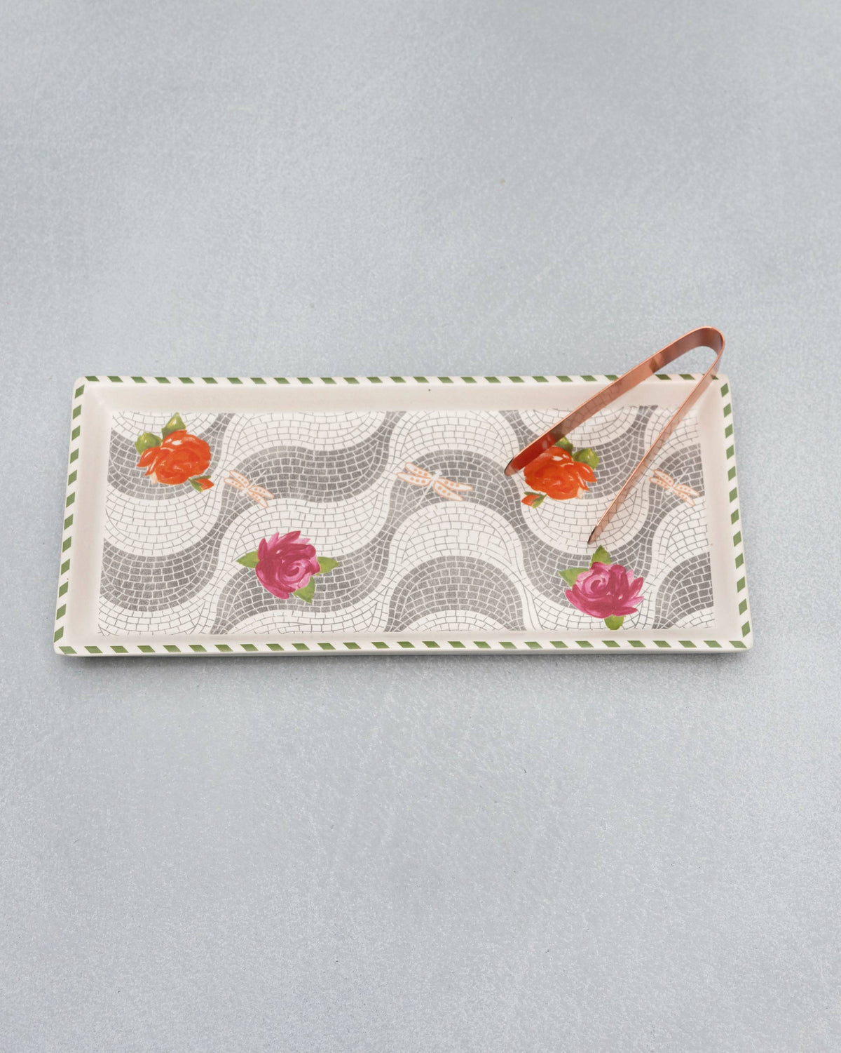Overhead view of the Mosaic Bloom cookie tray showing rose and dragonfly motifs with tongs.