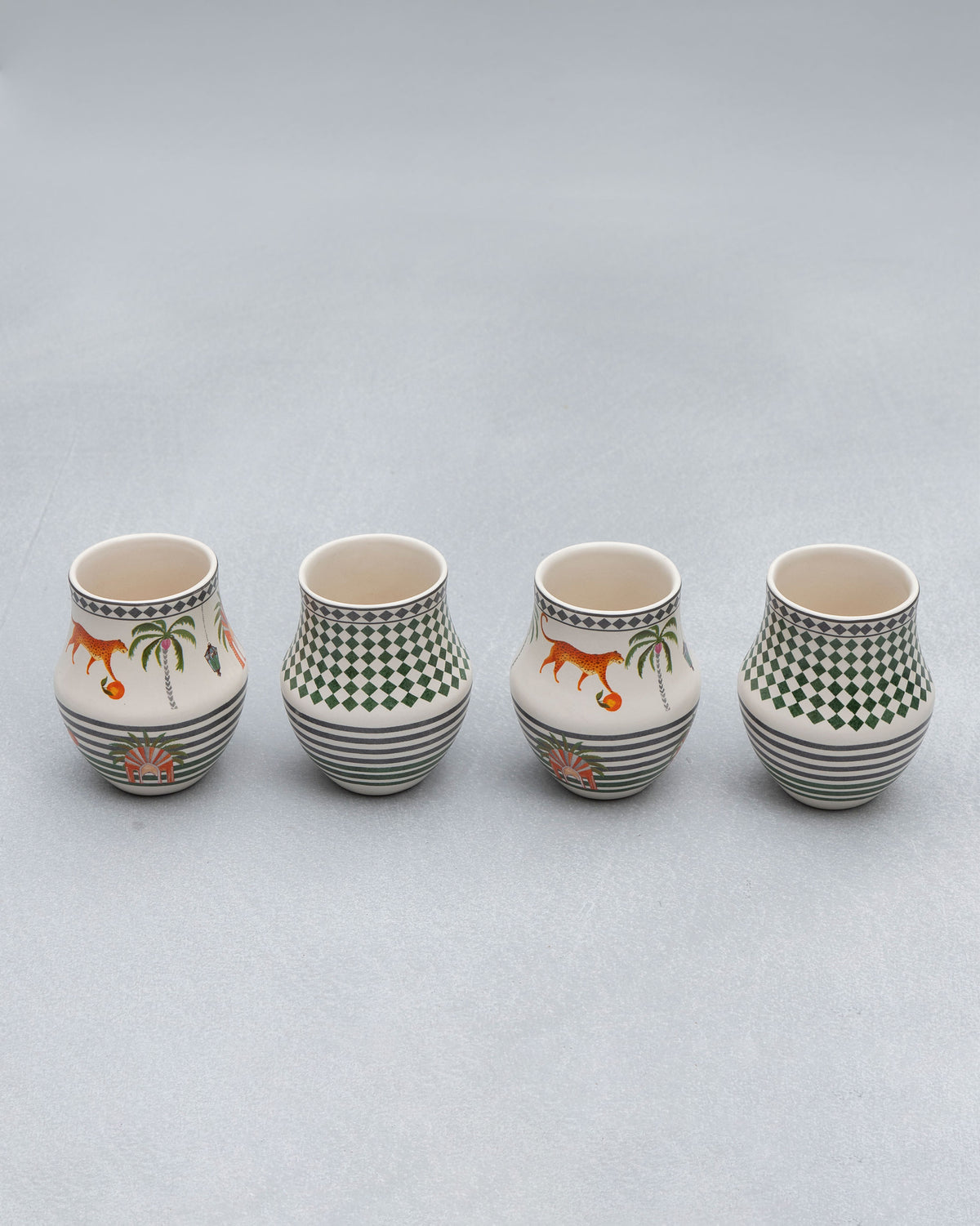 Four Dessert Palm Kulhars on a grey surface, two with tiger motifs.
