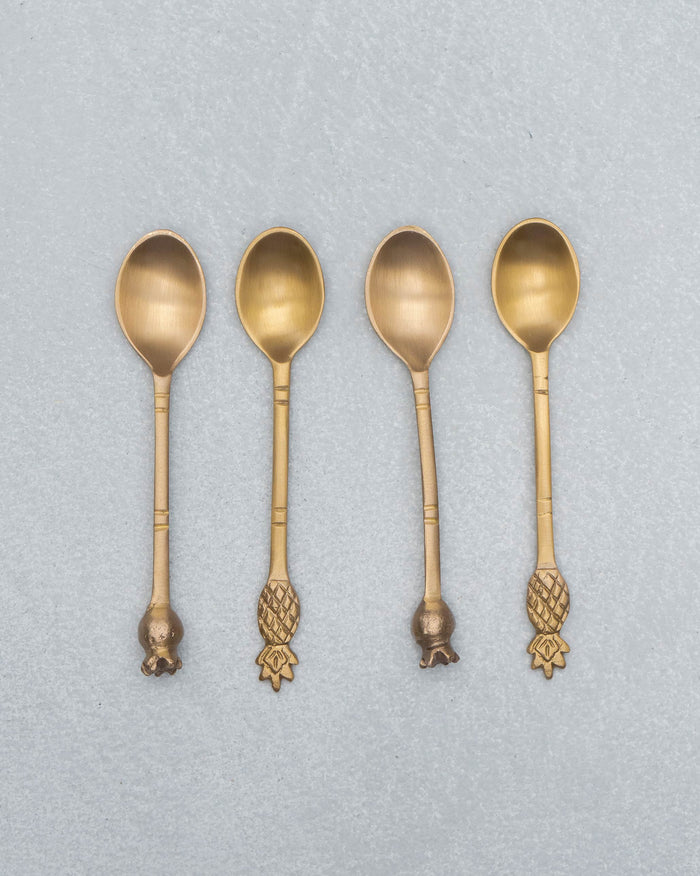 Four brass Dune coffee spoons with pineapple and pomegranate finials.