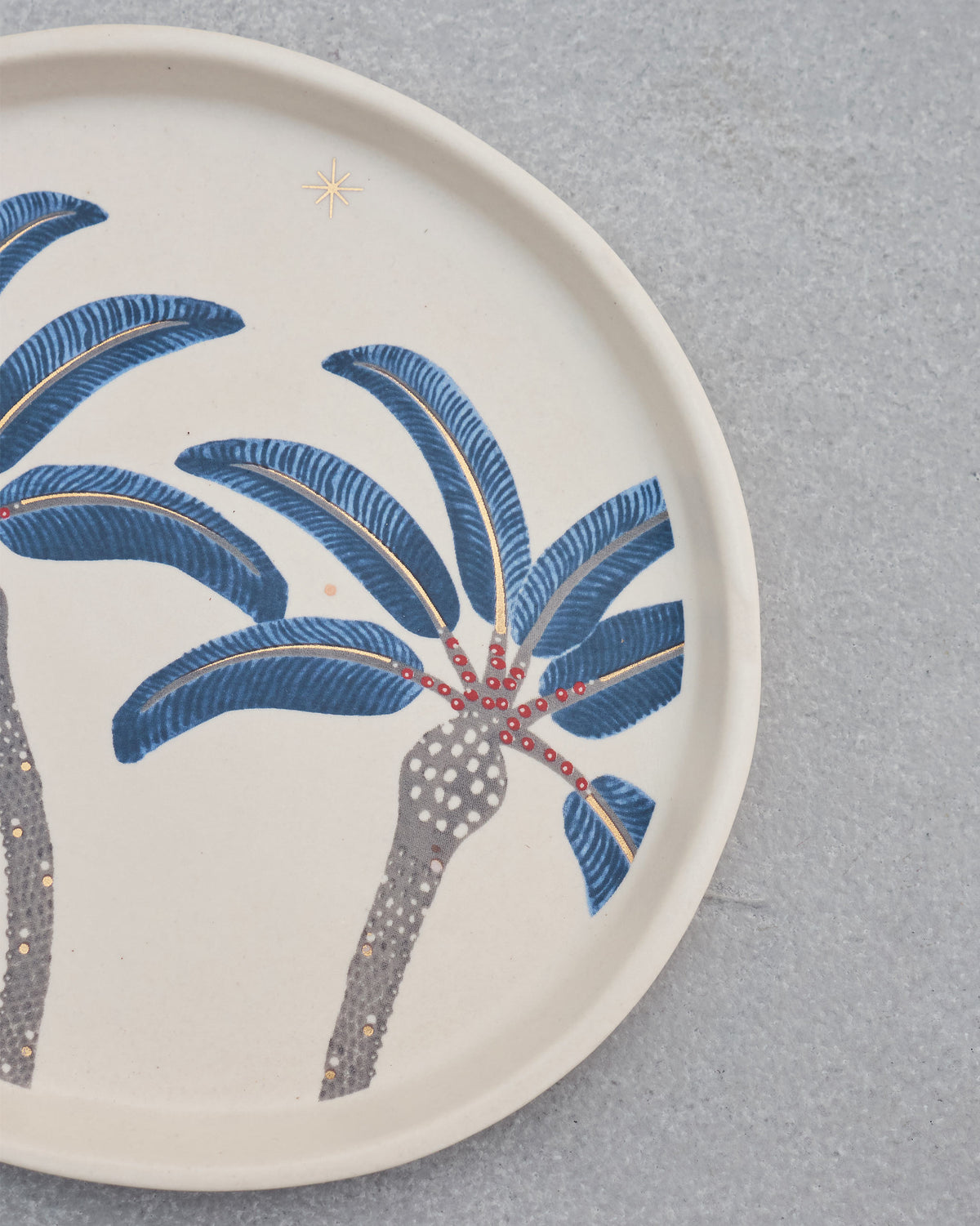 Close-up of Dancing Palm Dessert Plate showing blue fronds and red dotted palm crowns.