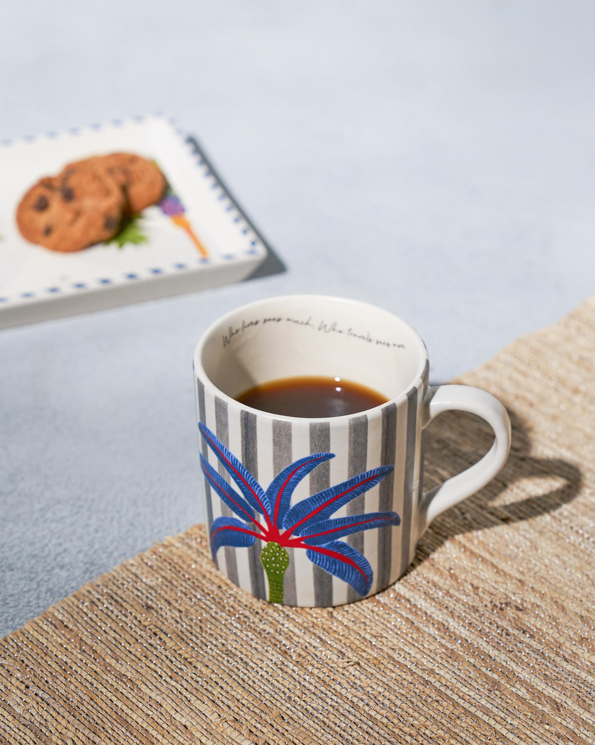 Dancing Palm Straight Mug filled with coffee, showing grey stripes and a blue palm motif.