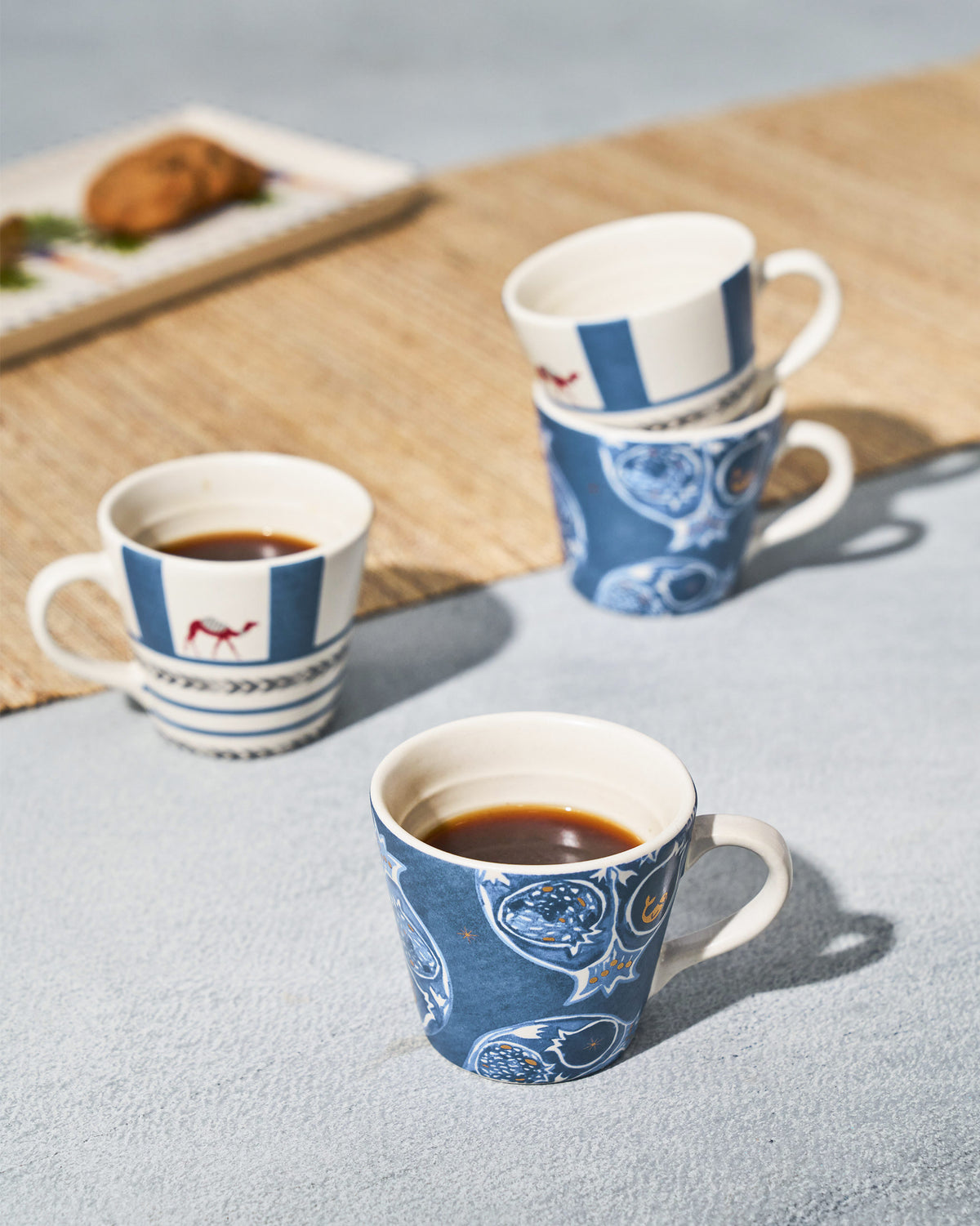 Desert Trail Espresso Mugs with camel and pomegranate prints filled with coffee.