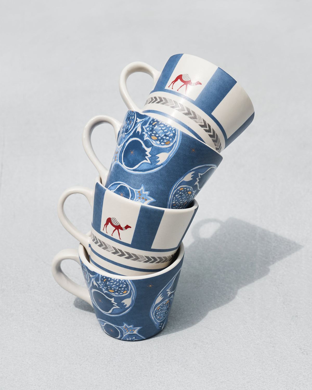 Stack of four Desert Trail Espresso Mugs with camel and pomegranate prints.