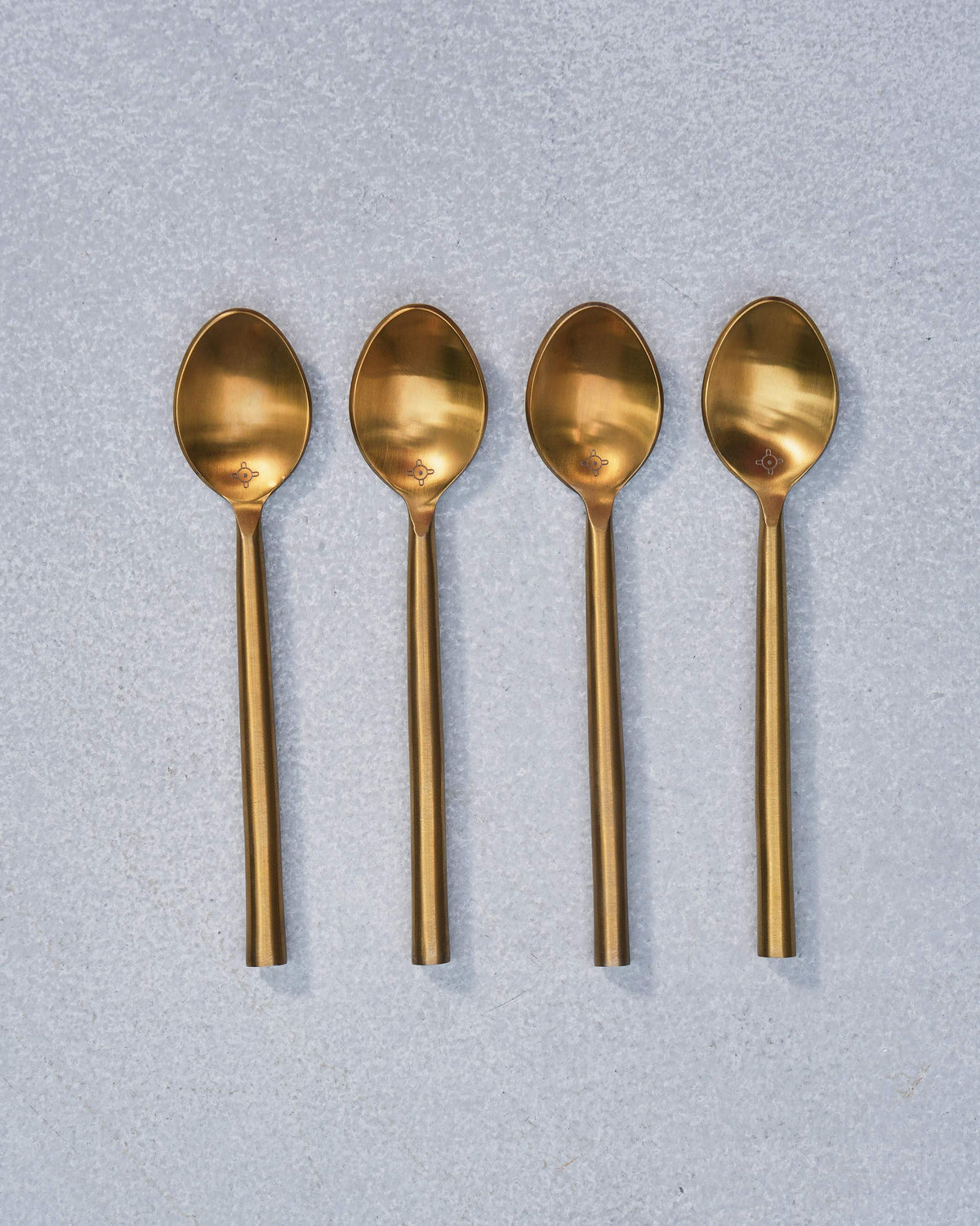 Four aligned gold Sahara spoons showing oval bowls and slim handles.