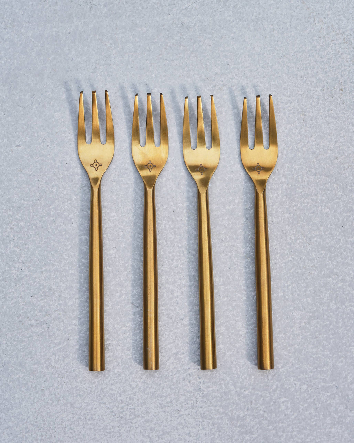 Set of four gold Sahara dessert forks lined up side by side.