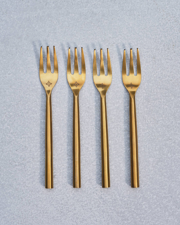 Set of four gold Sahara dessert forks lined up side by side.
