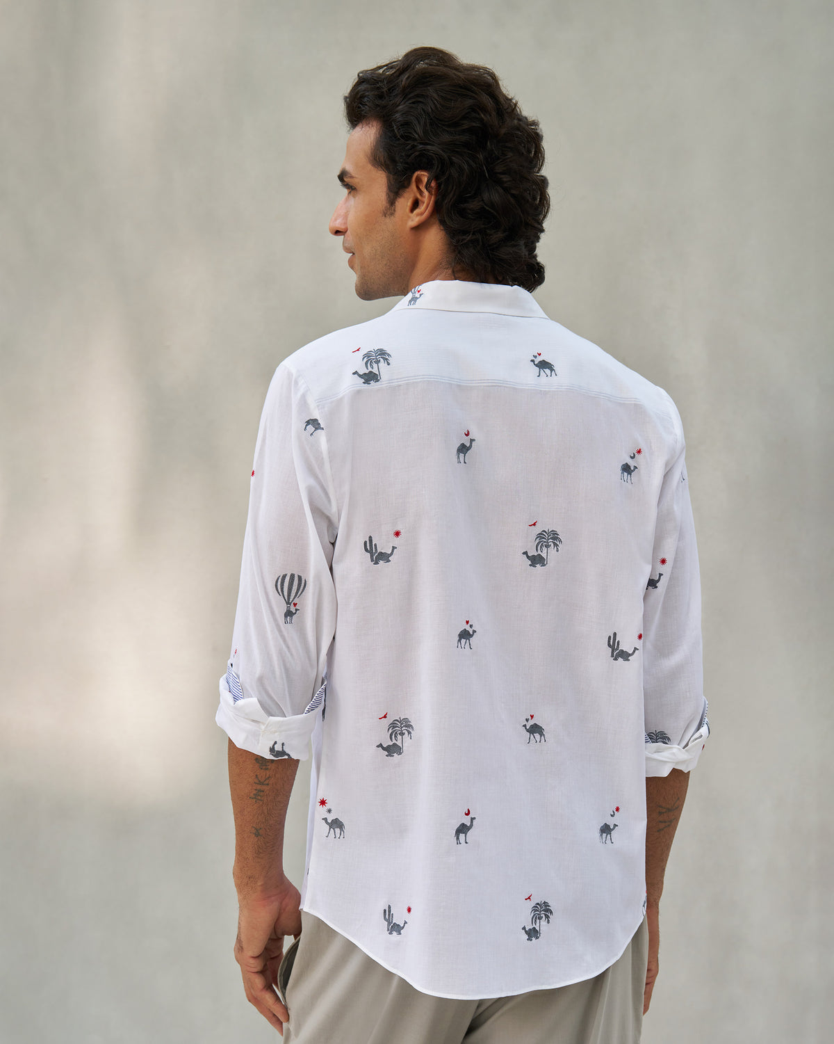 Back of a white Hakuna shirt with camel and palm motifs.