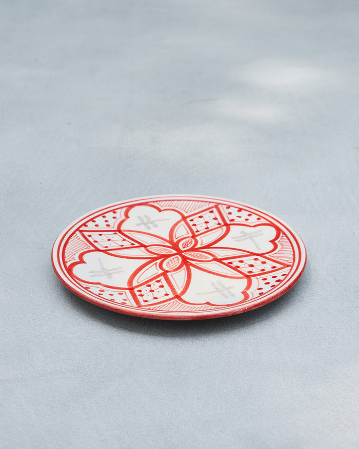 Angled view of a red Mosaic Oasis quarter plate with a geometric floral pattern.