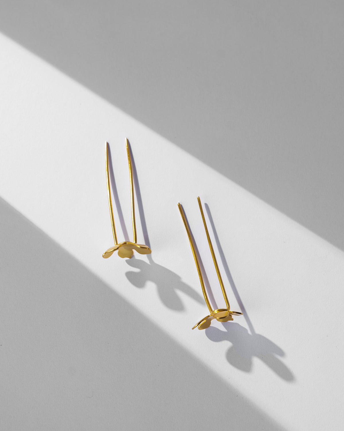 Pair of gold Small Poppy hairpins laid flat.